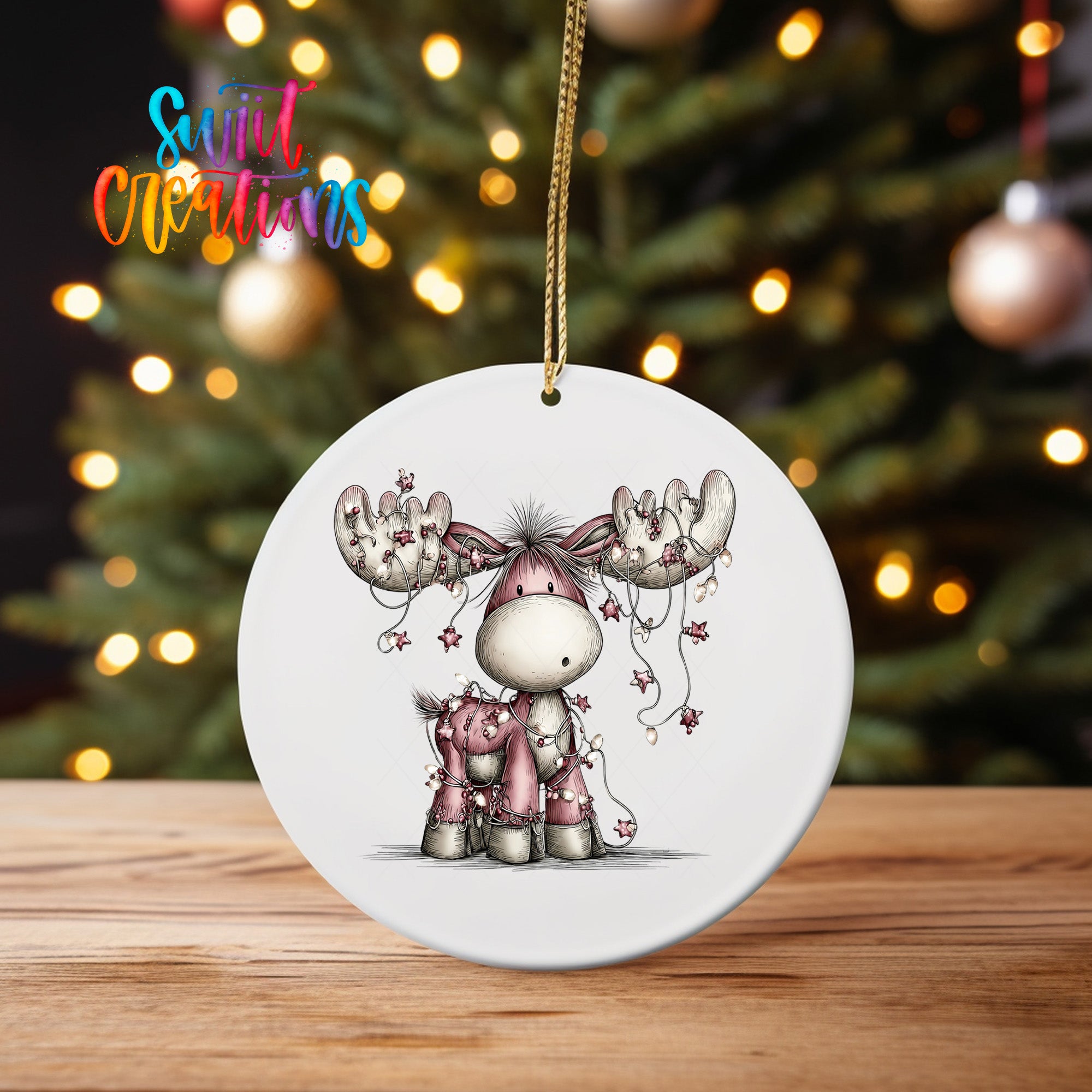 A white ornament featuring a cartoon moose with antlers and a smaller moose, surrounded by Christmas lights and ornaments.