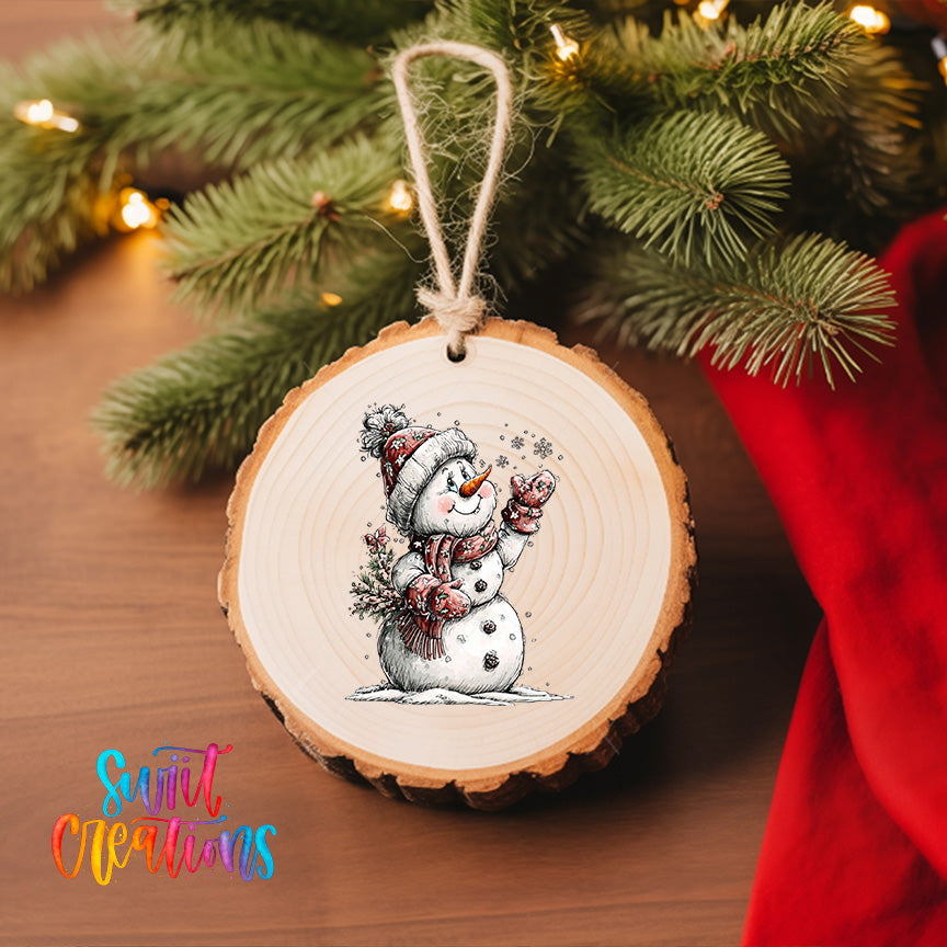A wooden ornament featuring a snowman is hanging on a Christmas tree, surrounded by pine branches and twinkling lights.