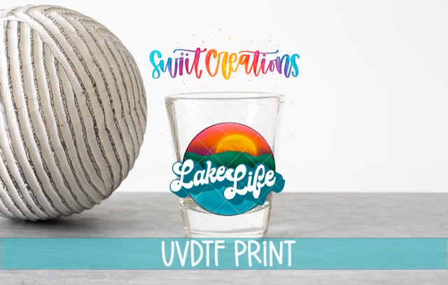 a glass with a colorful design and text, along with a large white ball and a blue banner with text.