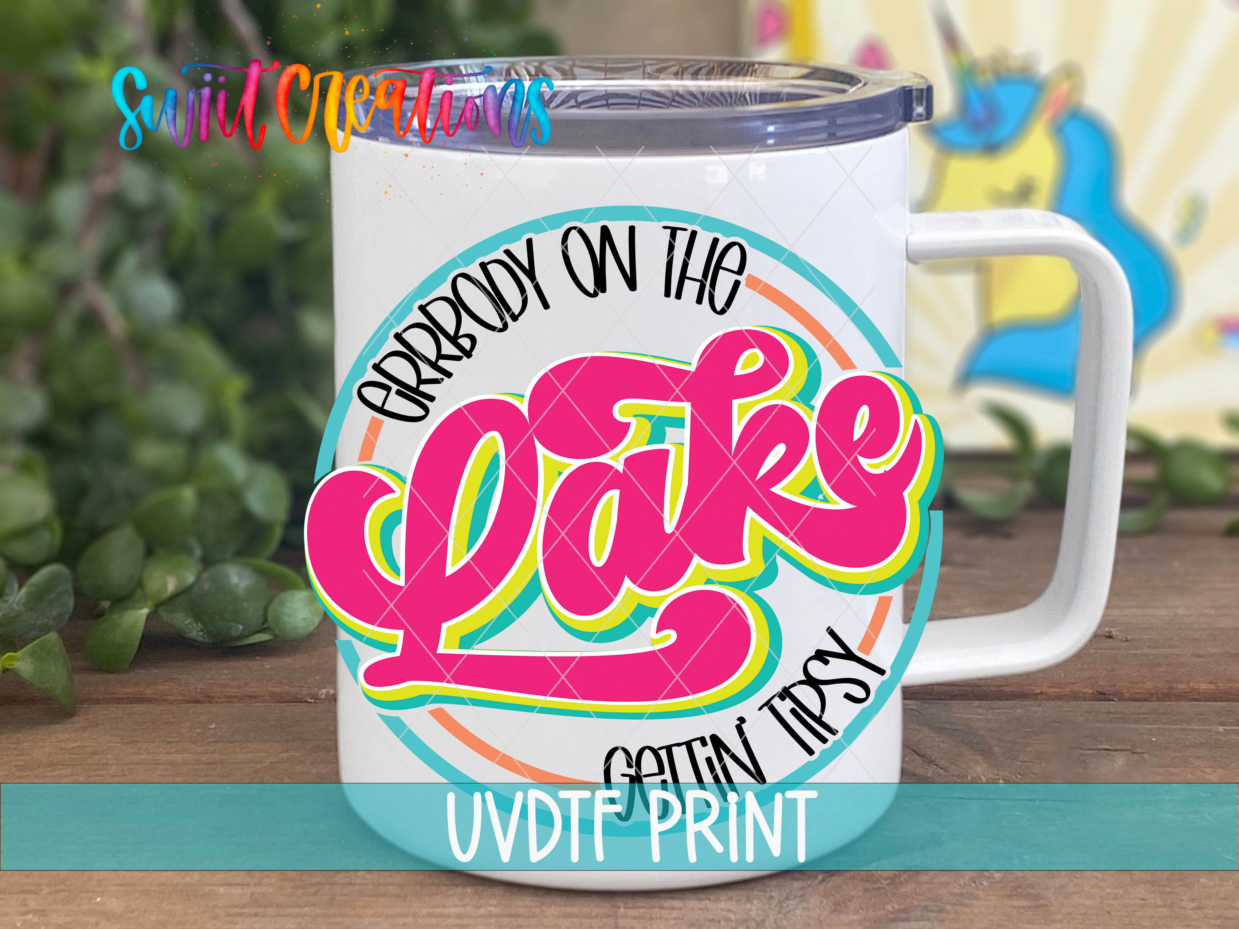 A white mug with a colorful graphic design featuring the text "Grrbody on the Lake" and "Gotta Tipsy" printed on it.