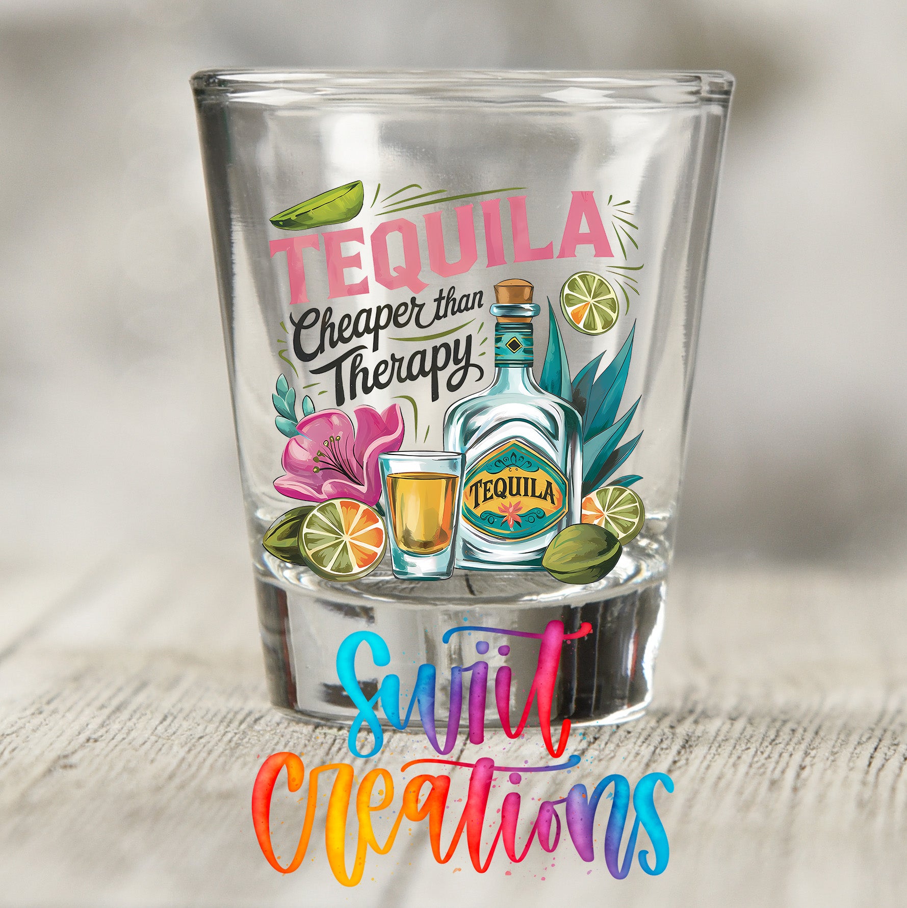 a shot glass with a colorful design and text that reads "TEQUILA Cheaper than Therapy" and "Suji Creations".