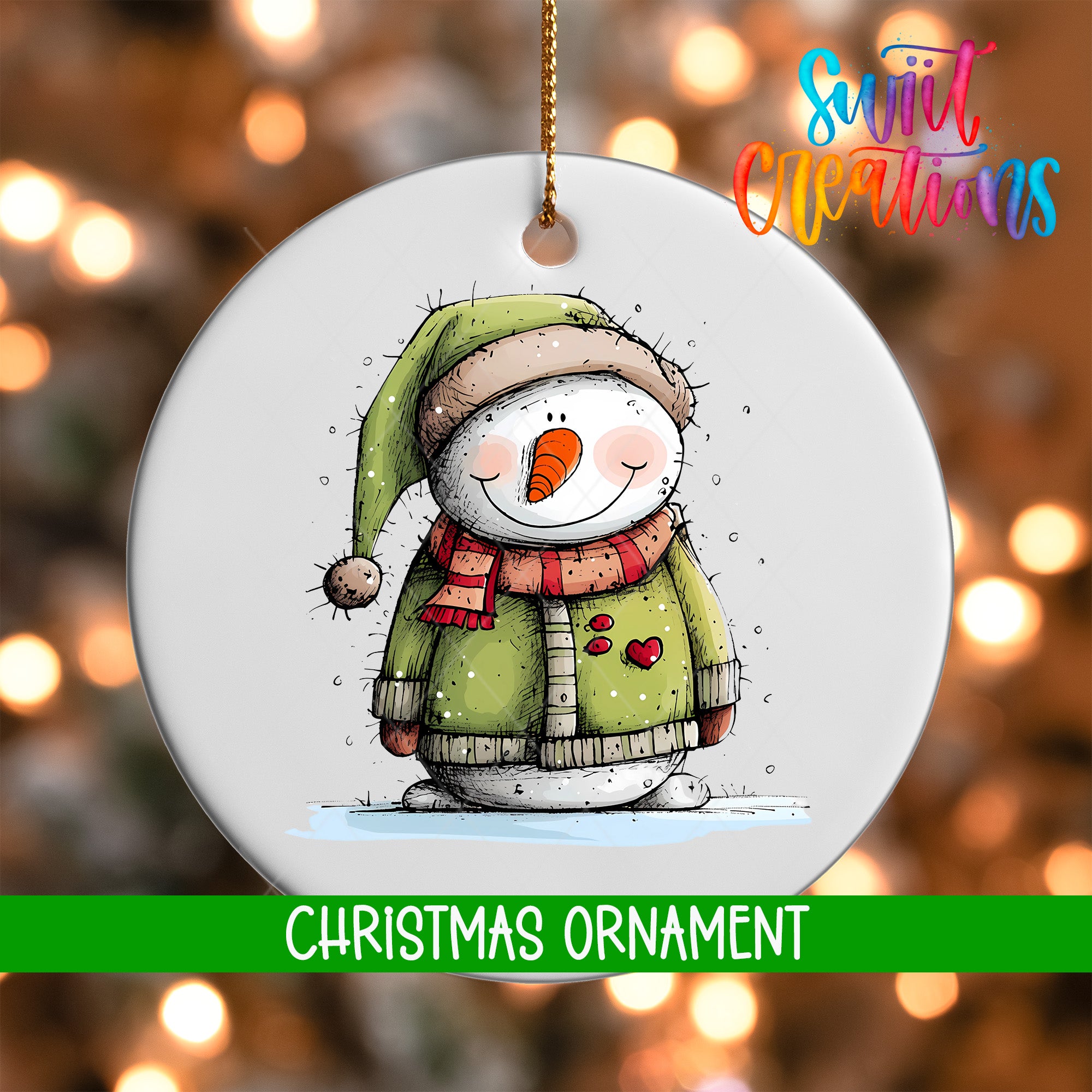 A white Christmas ornament featuring a snowman wearing a green hat and scarf, with a red heart on its chest, against a blurred background of Christmas lights.