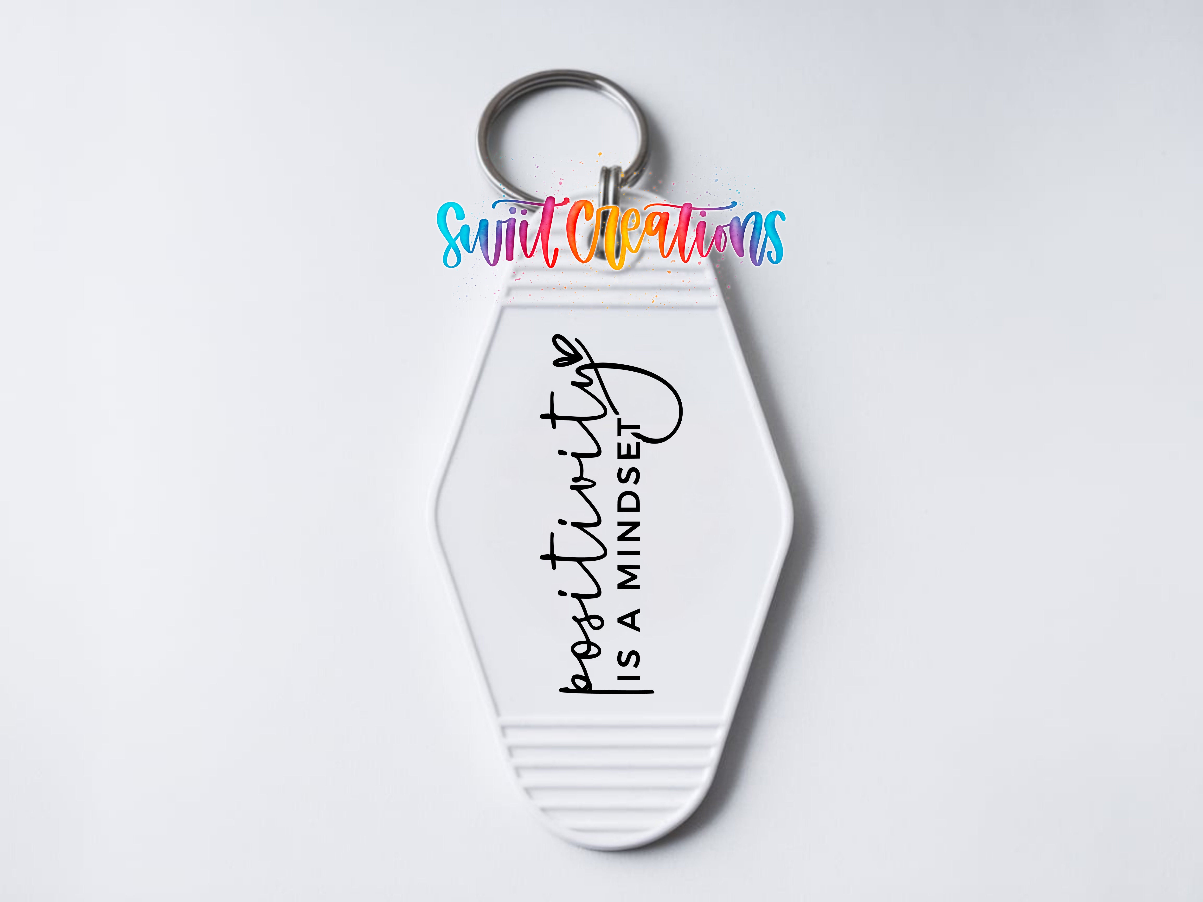 A white keychain with a motivational message printed on it.