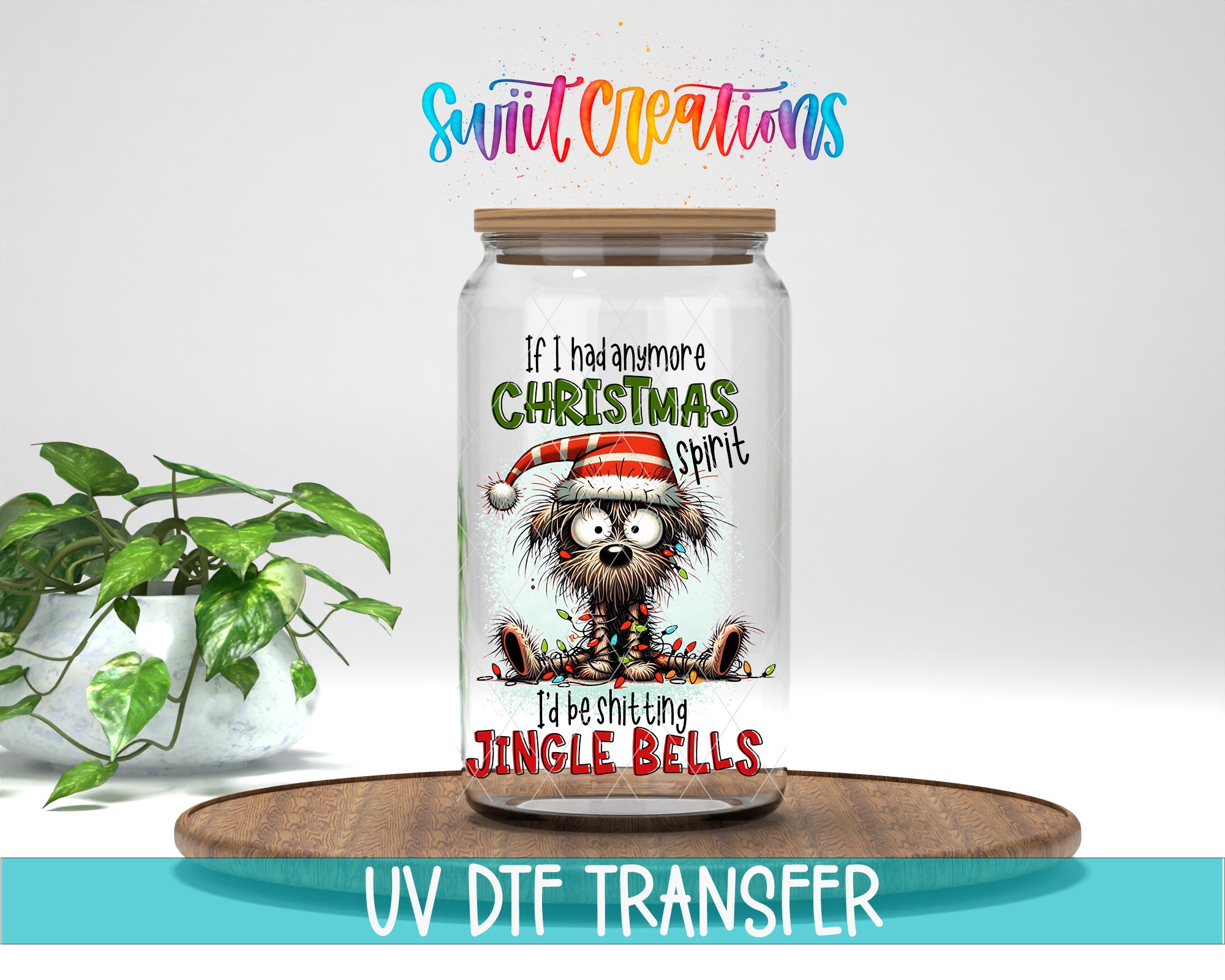 A glass jar with a cartoon image of a dog wearing a Santa hat and the text "If I had any more Christmas spirit, I'd be singing Jingle bells" printed on it. The jar is placed on a wooden surface, and there is a potted plant in the background.