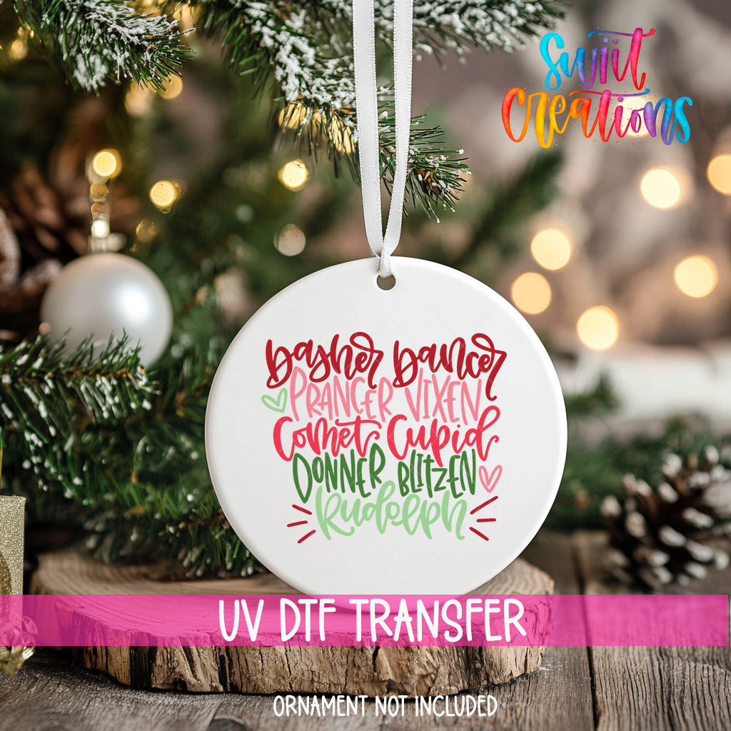 A white ceramic ornament with a colorful, hand-lettered design hangs on a Christmas tree.