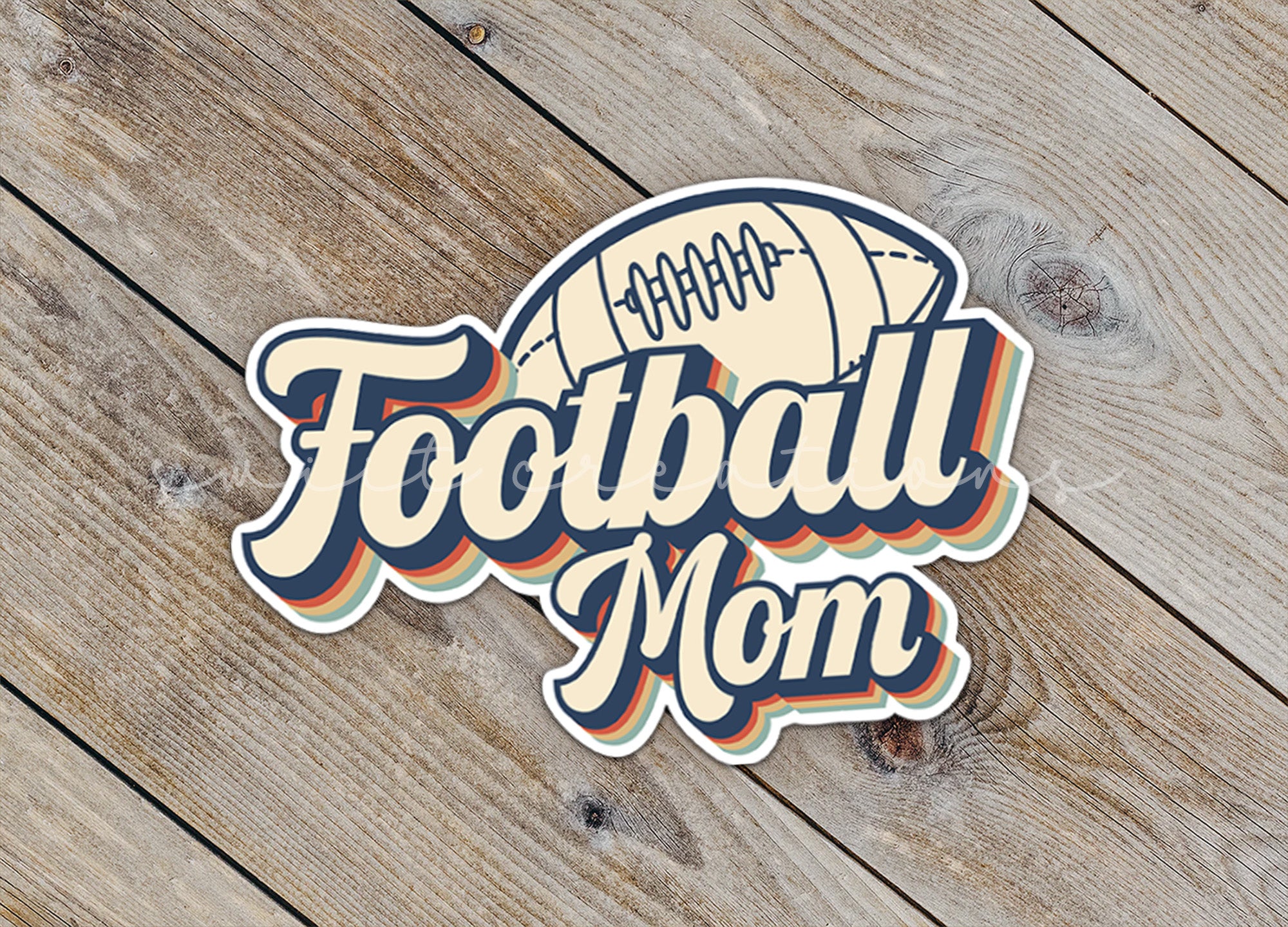 a football mom sticker sitting on top of a wooden table