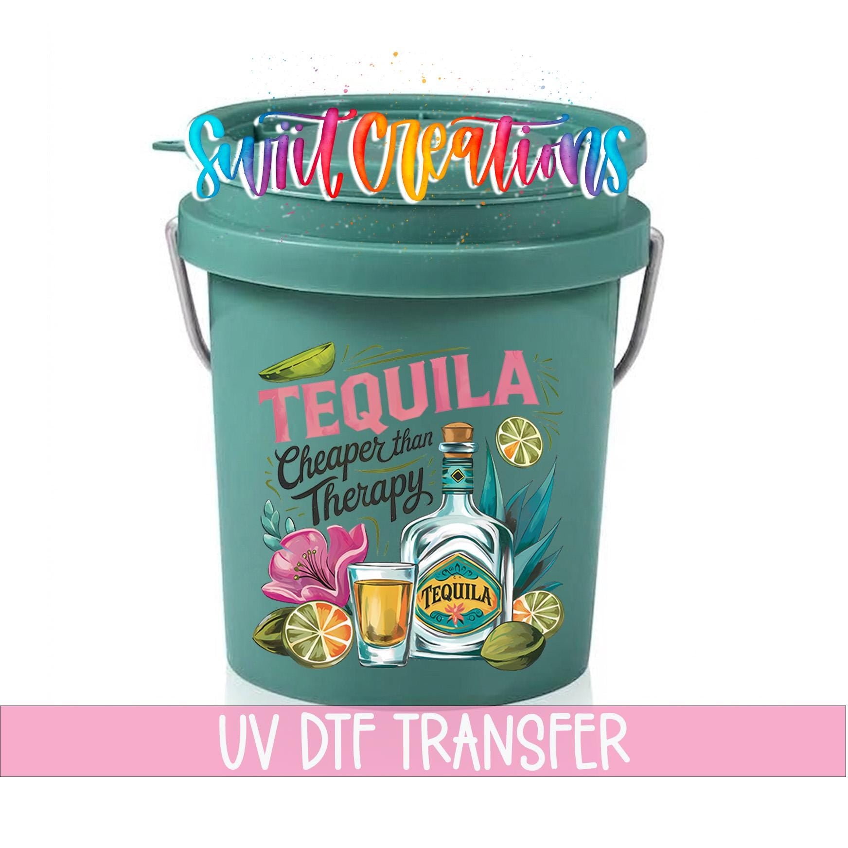 A green bucket with a colorful design featuring a bottle of tequila, a lime, and other tropical elements. The bucket has a handle on top and a UV dye transfer label.
