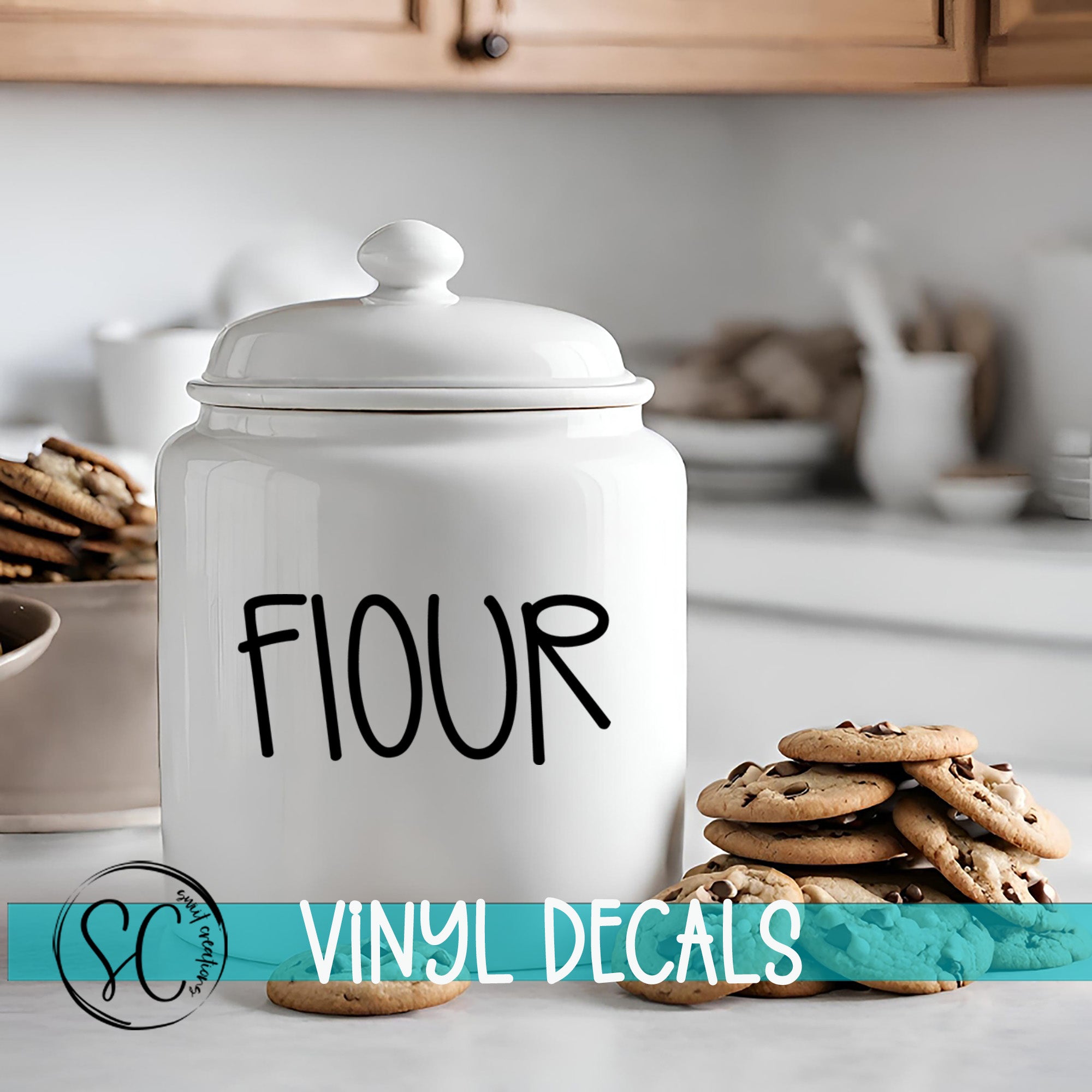 A white ceramic flour container with the word "FLOUR" printed on it, placed on a kitchen counter next to a stack of chocolate chip cookies.