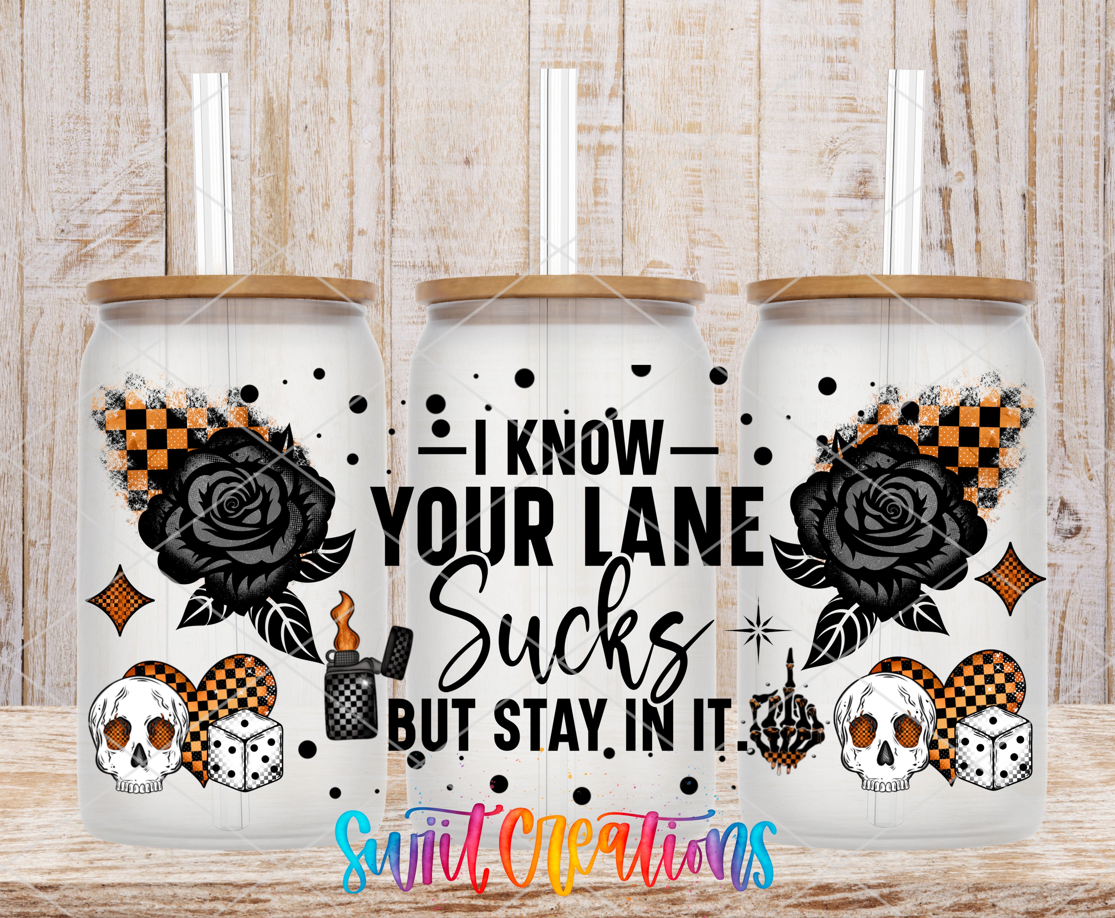 three glass tumblers with black and orange designs, including a rose, dice, and skull, along with text that reads "I KNOW YOUR LANE SUCKS BUT STAY IN IT".