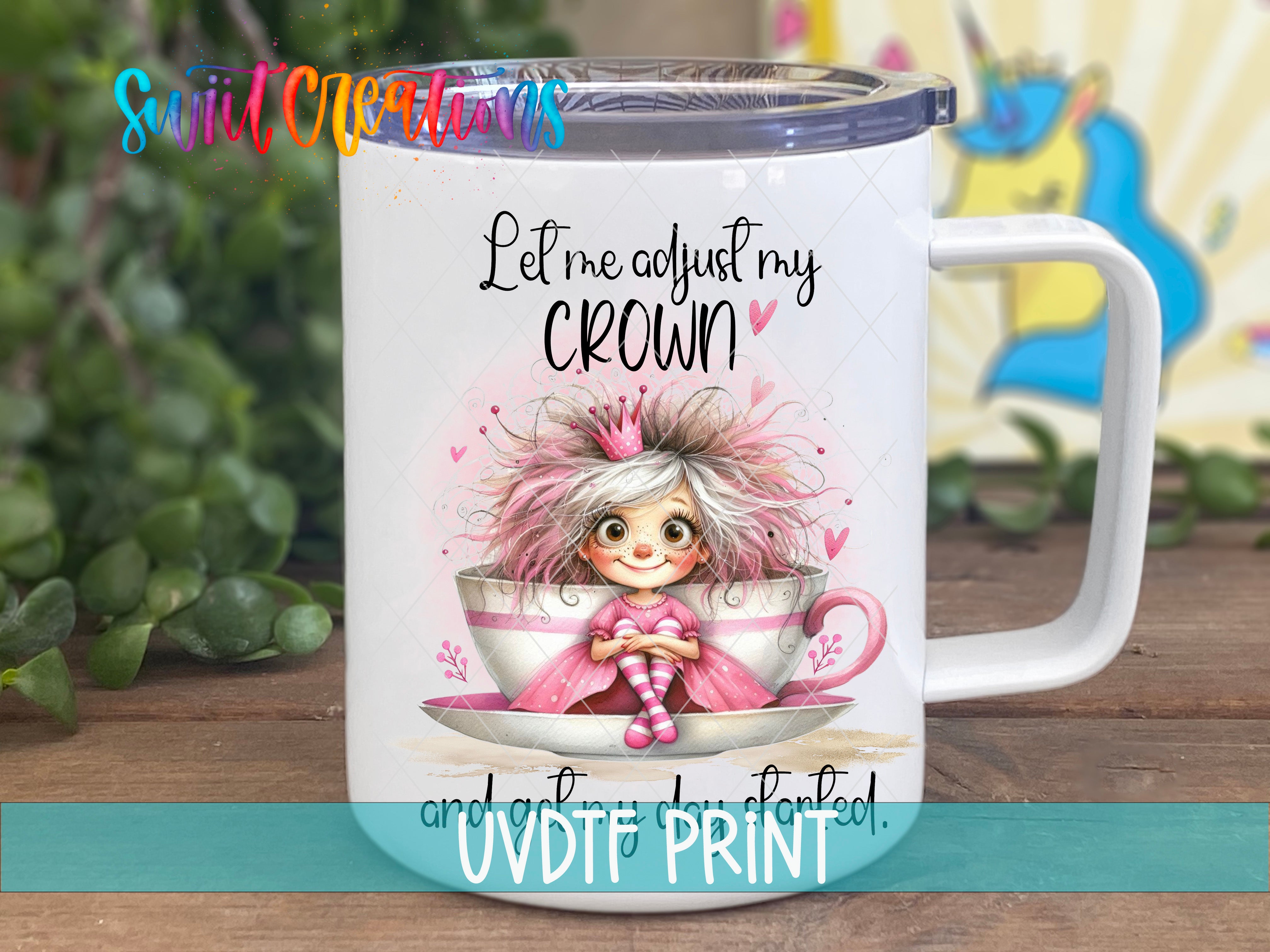 A white mug with a cartoon image of a girl wearing a pink dress and a crown, sitting inside a teacup. The mug has a printed message that says "Let me adjust my crown and get started."