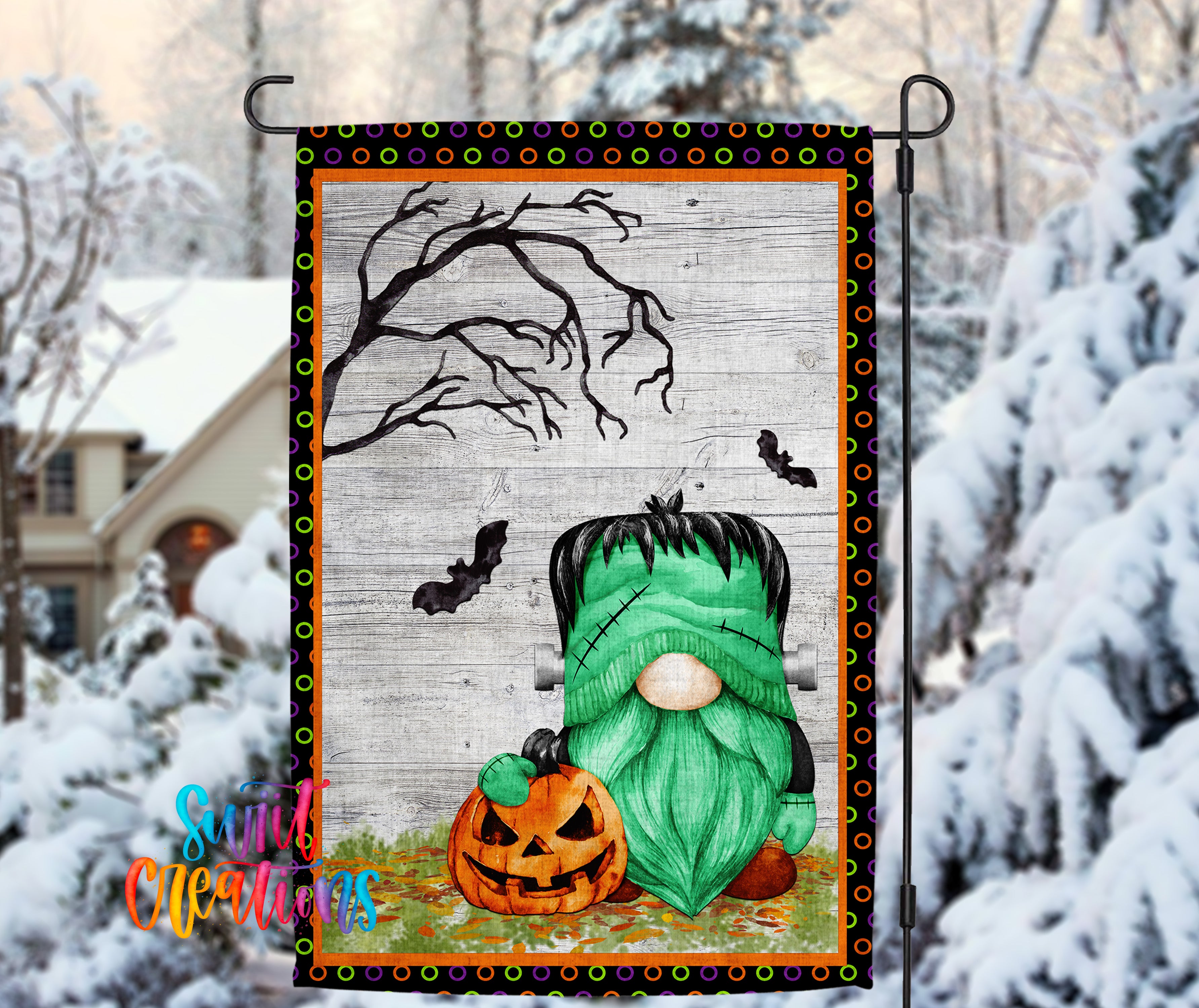 A Halloween-themed garden decoration featuring a green gnome holding a carved pumpkin, with a spooky tree and bats in the background.