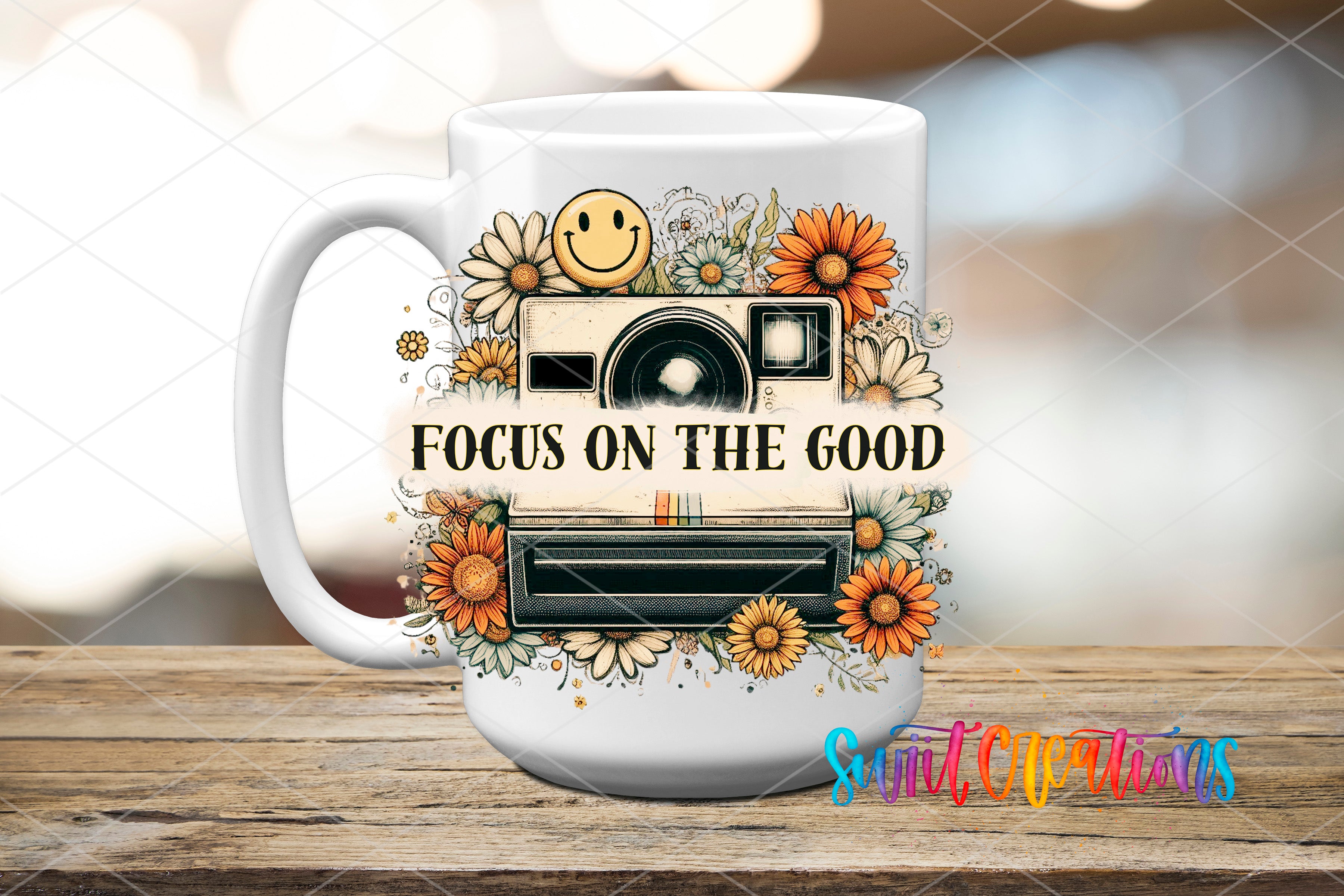 A white ceramic mug with a floral design and a camera, along with the text "FOCUS ON THE GOOD" printed on it.