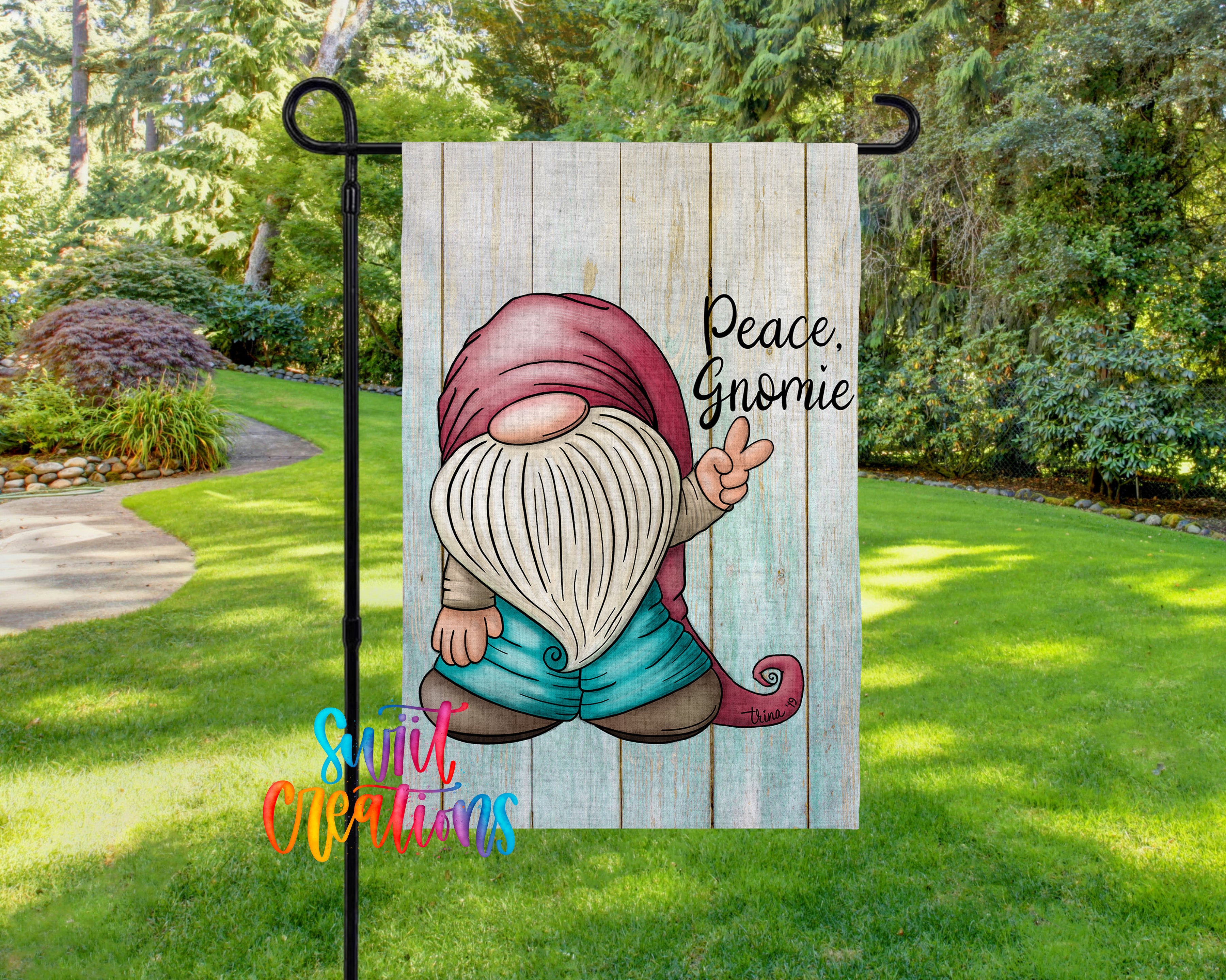 A garden gnome holding a peace sign is displayed on a wooden sign in a lush, green garden setting.