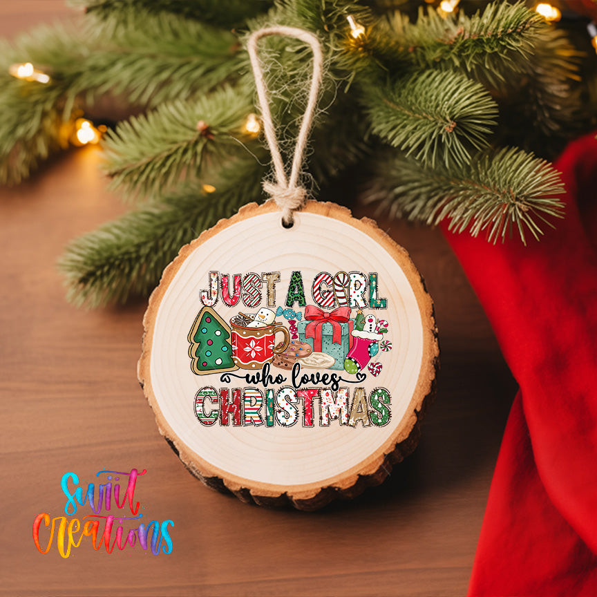 A wooden ornament with a text design hangs on a Christmas tree, surrounded by pine branches and twinkling lights.