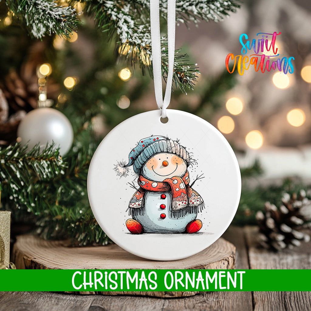 A white Christmas ornament featuring a smiling snowman is hanging from a tree branch, with a blurred background of lights and greenery.
