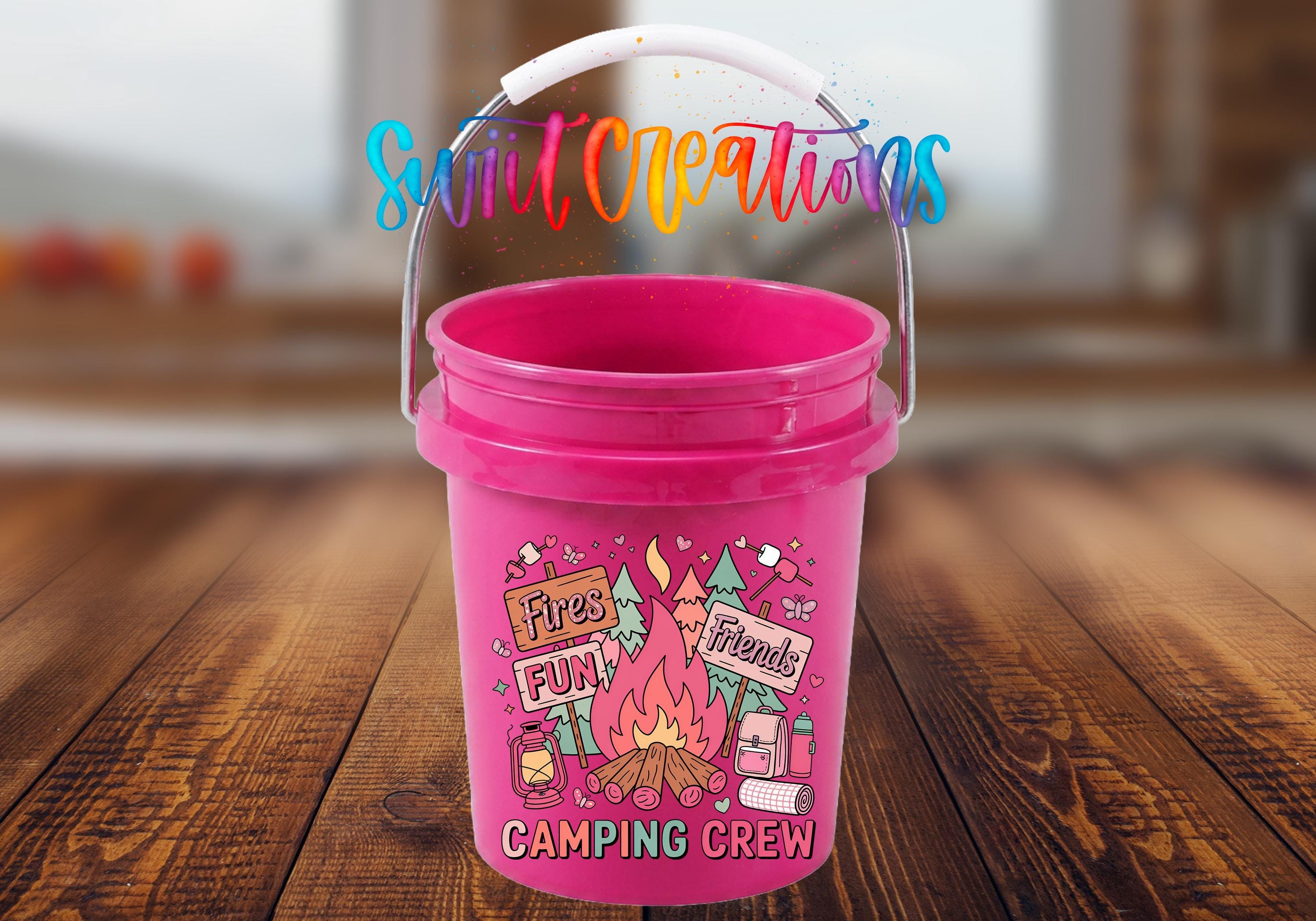 A pink bucket with a handle, featuring a colorful design with camping-related elements such as a campfire, tent, and camp stove.