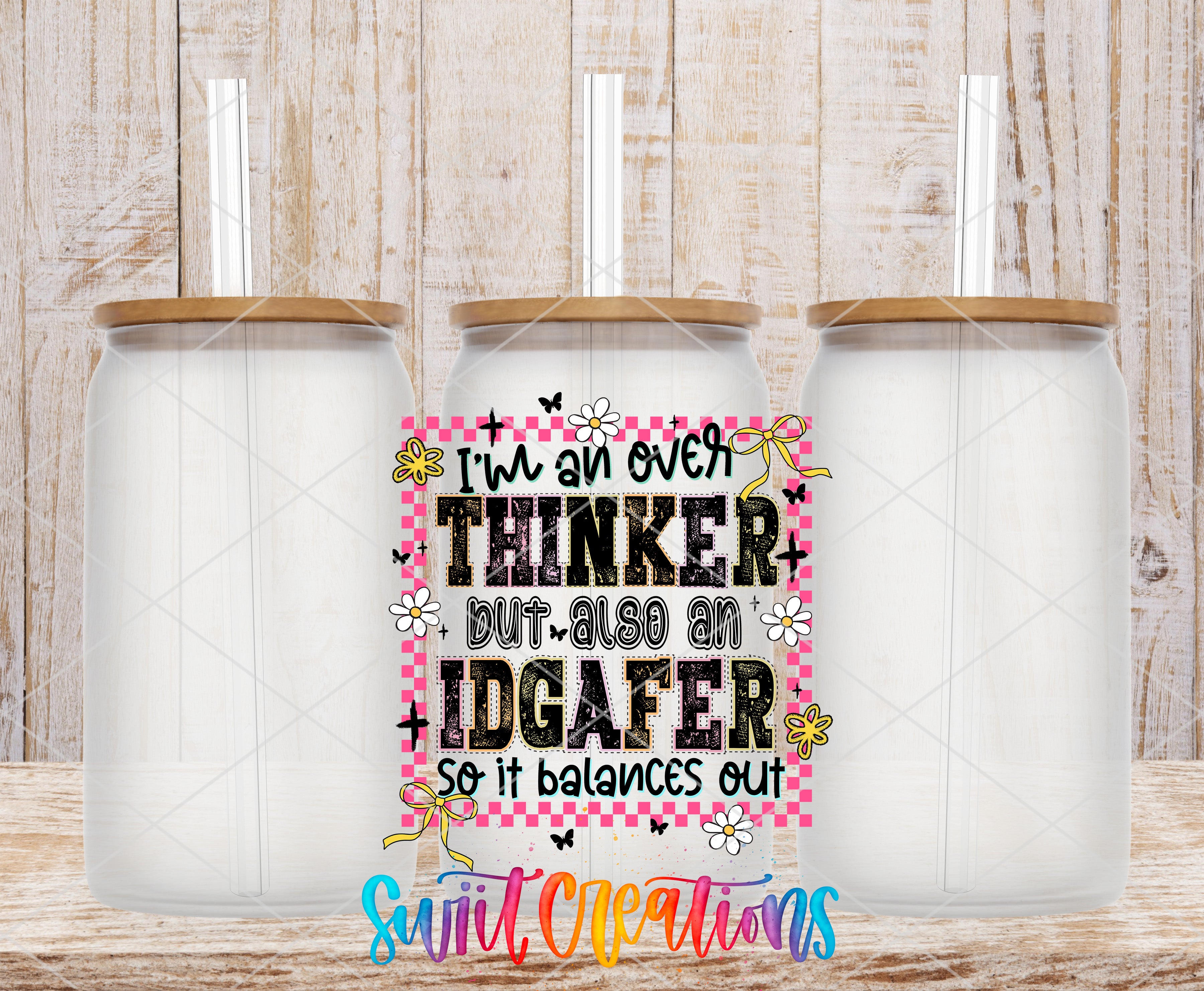 three glass jars with lids, arranged in a row against a wooden background. In the center of the image, there is a colorful graphic design with text and illustrations, including the phrase "I'm an over THINKER but also an IDGAFER so it balances out" and the word "Suit Creations" at the bottom.