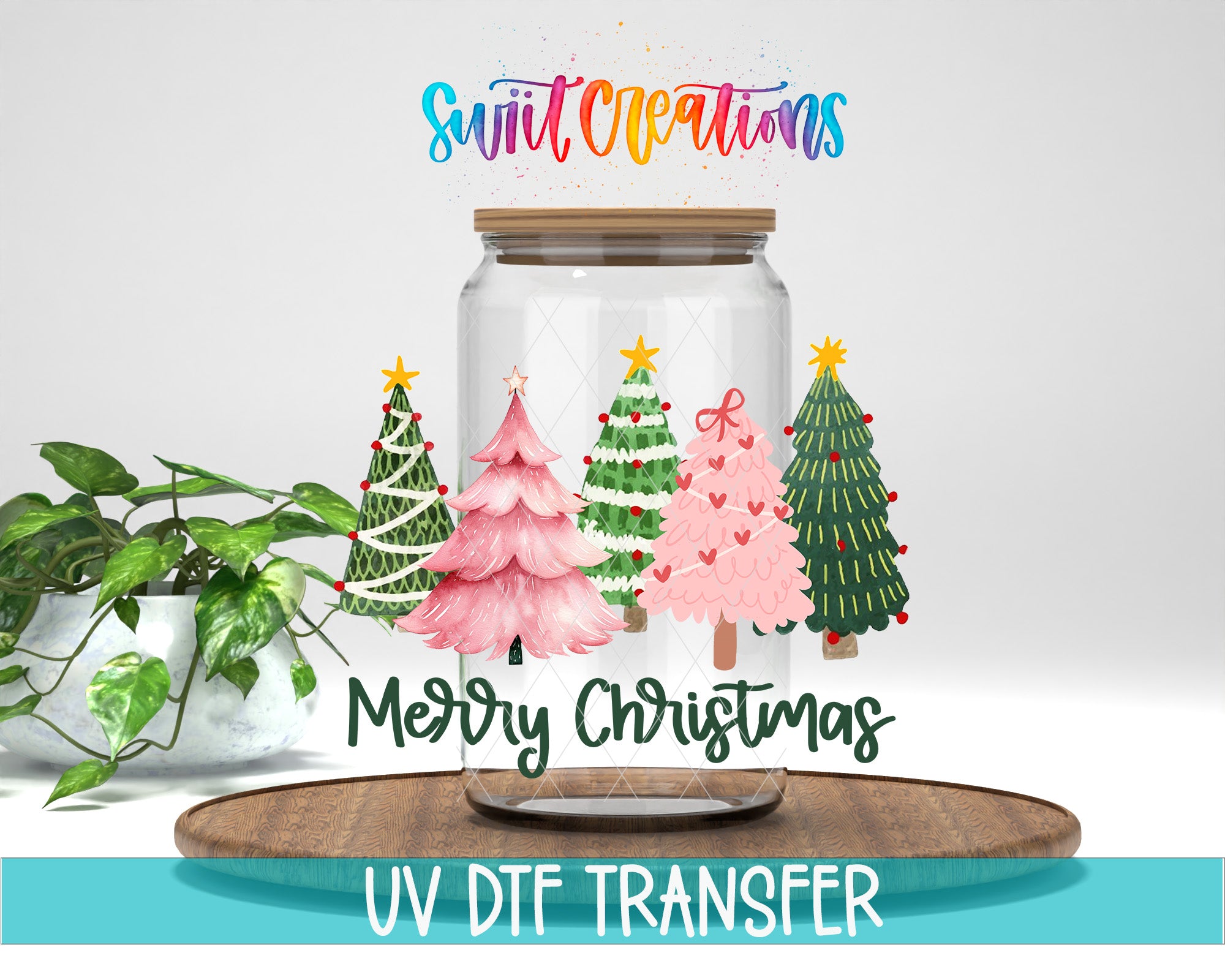 A glass jar filled with Christmas trees, along with a potted plant, sits on a wooden surface. The jar has a lid and the text "Merry Christmas" is displayed on it.