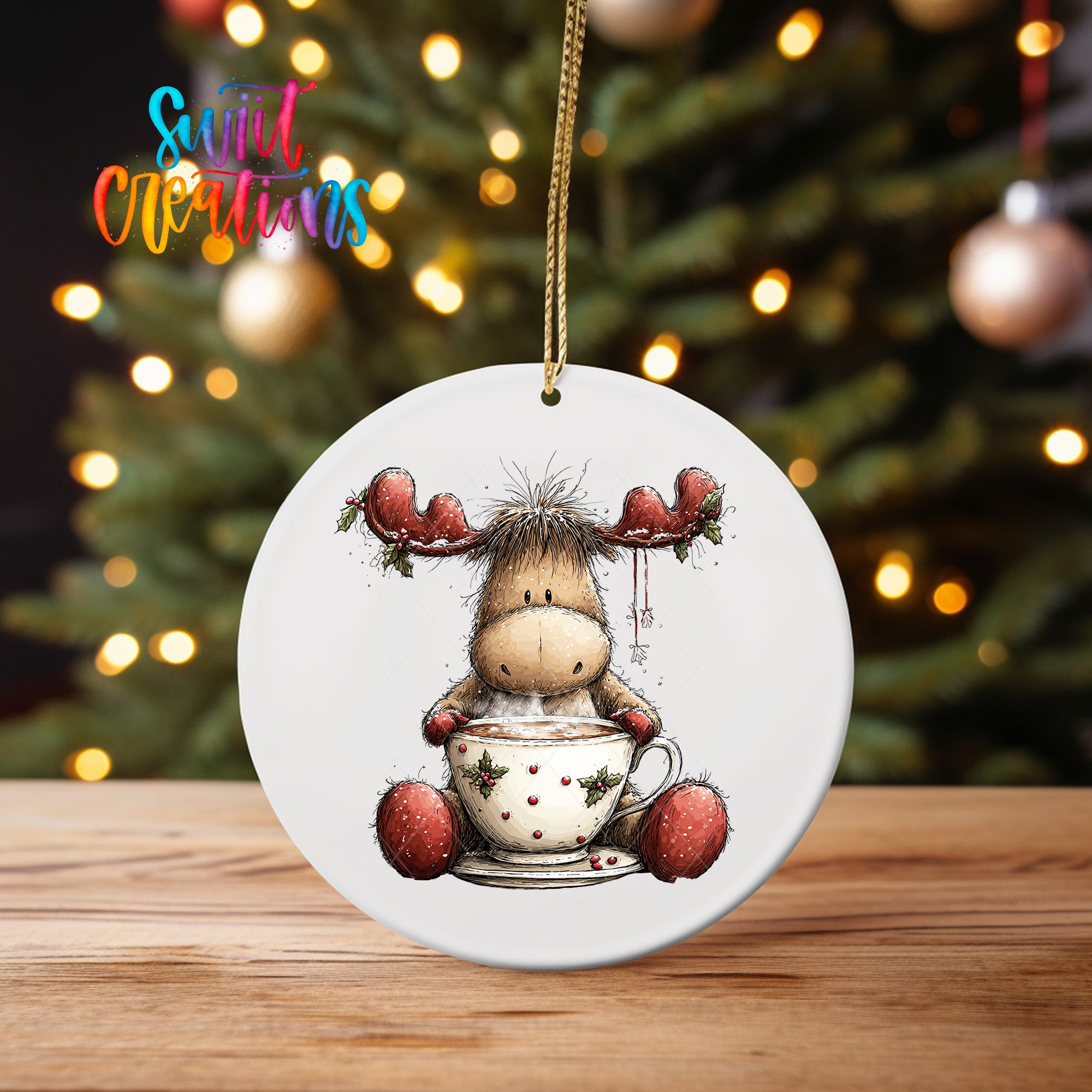 A white ceramic ornament featuring a cartoon moose sitting in a cup of hot chocolate, with Christmas lights in the background.