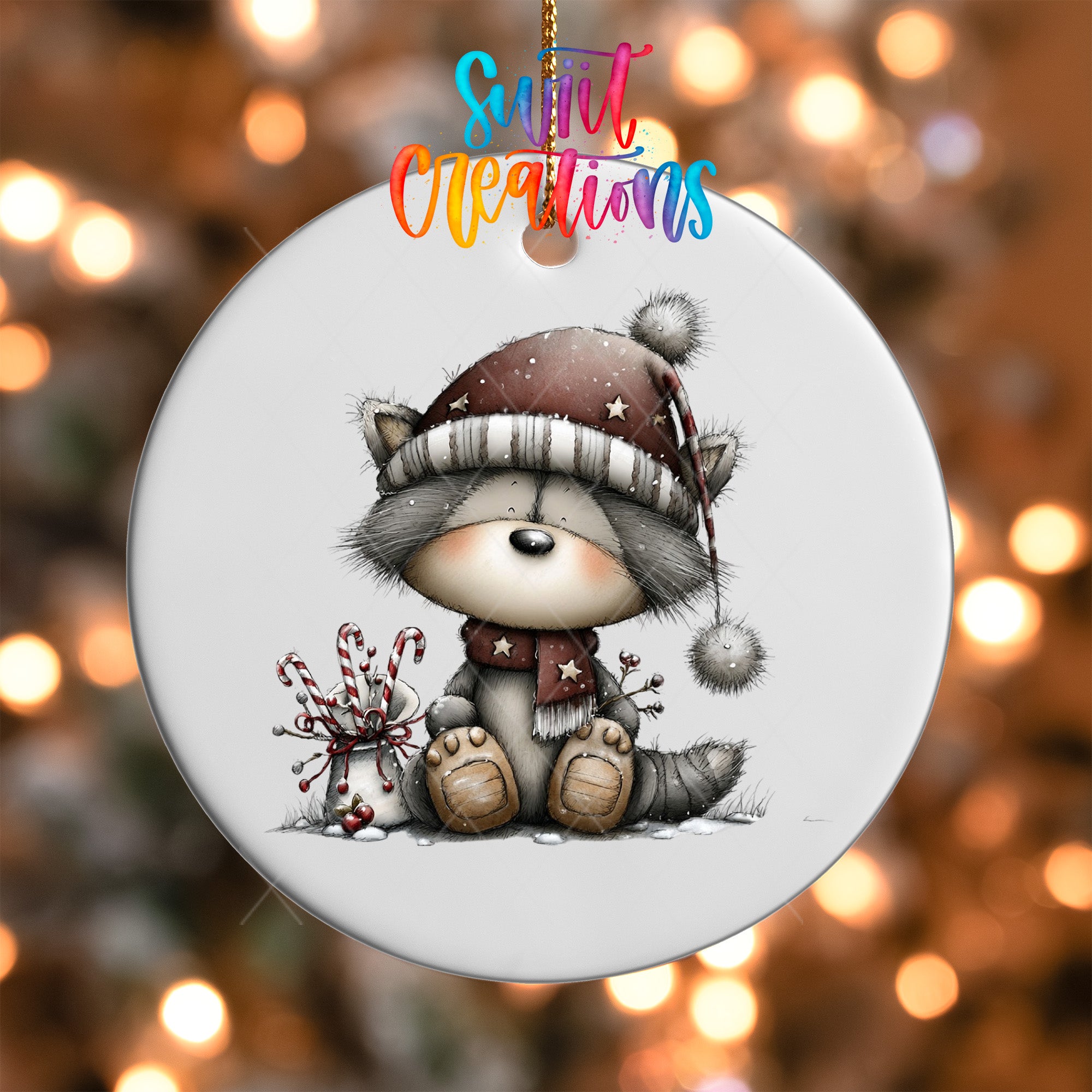 A ceramic ornament featuring a cute raccoon wearing a winter hat and scarf, sitting on the ground with a candy cane and other festive decorations.