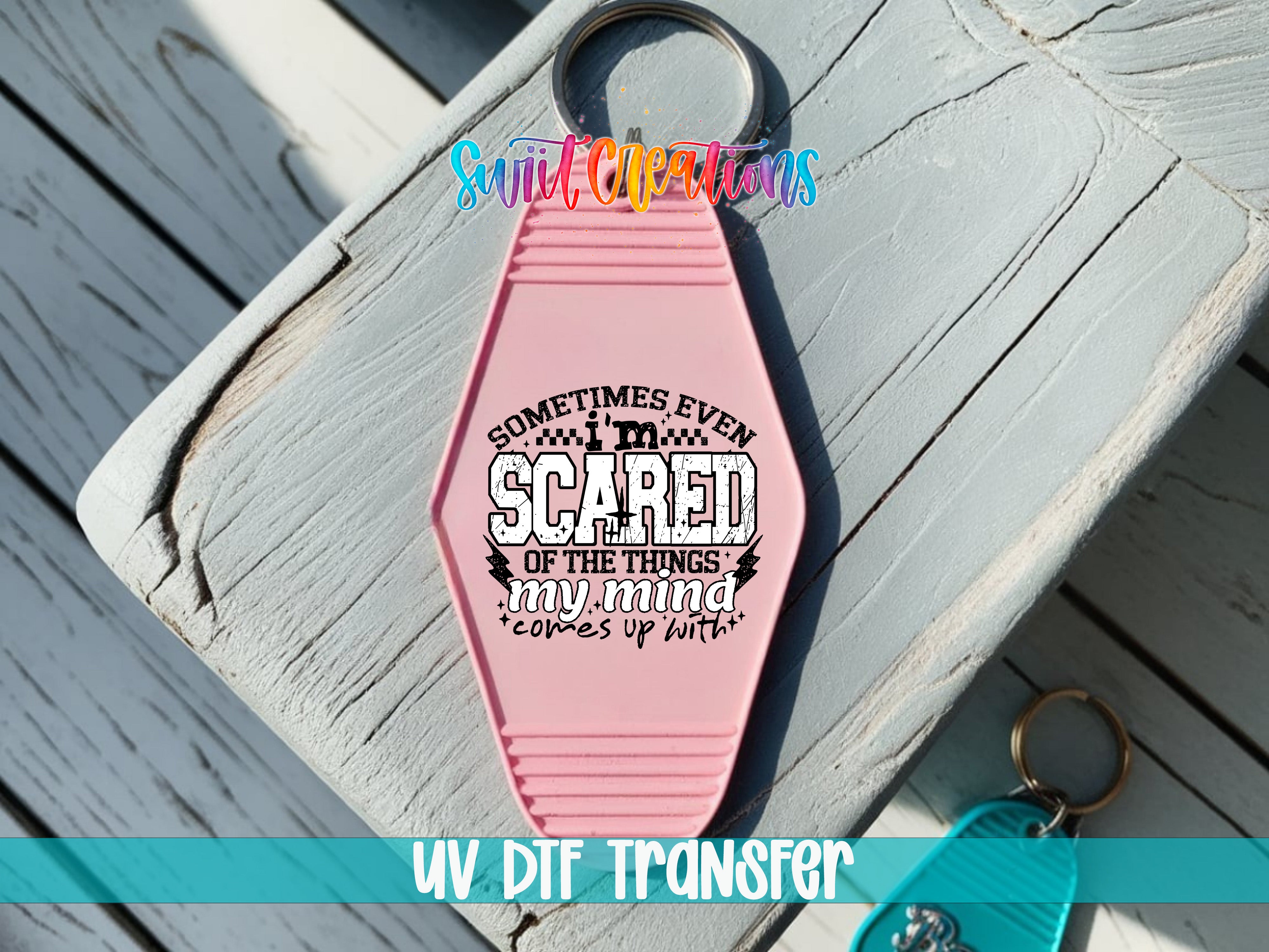 A pink keychain with a printed message on it, placed on a wooden surface.