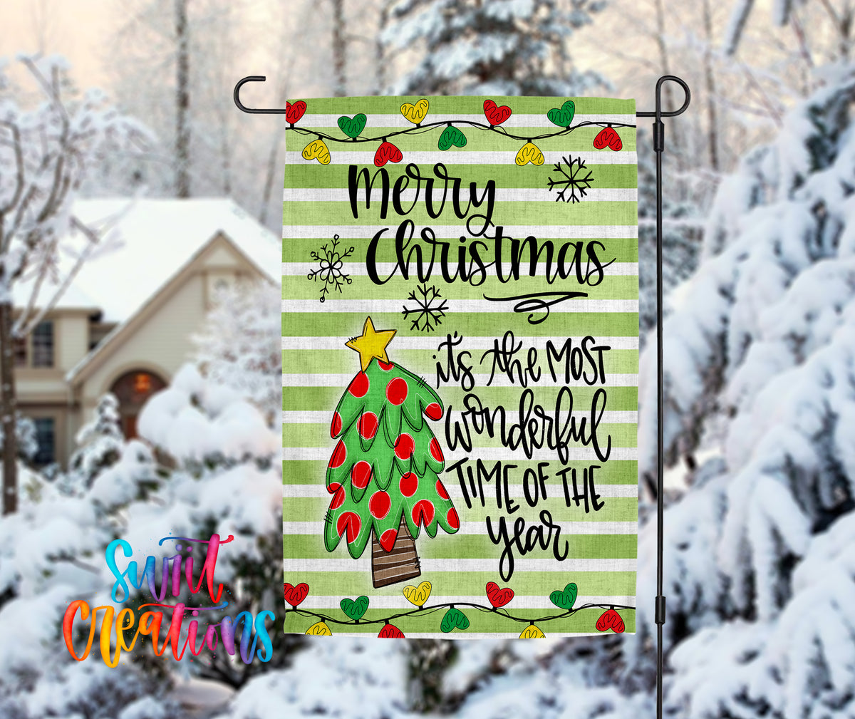 A festive Christmas-themed flag is displayed in a snowy outdoor setting, featuring a tree with red and green ornaments and a star on top.