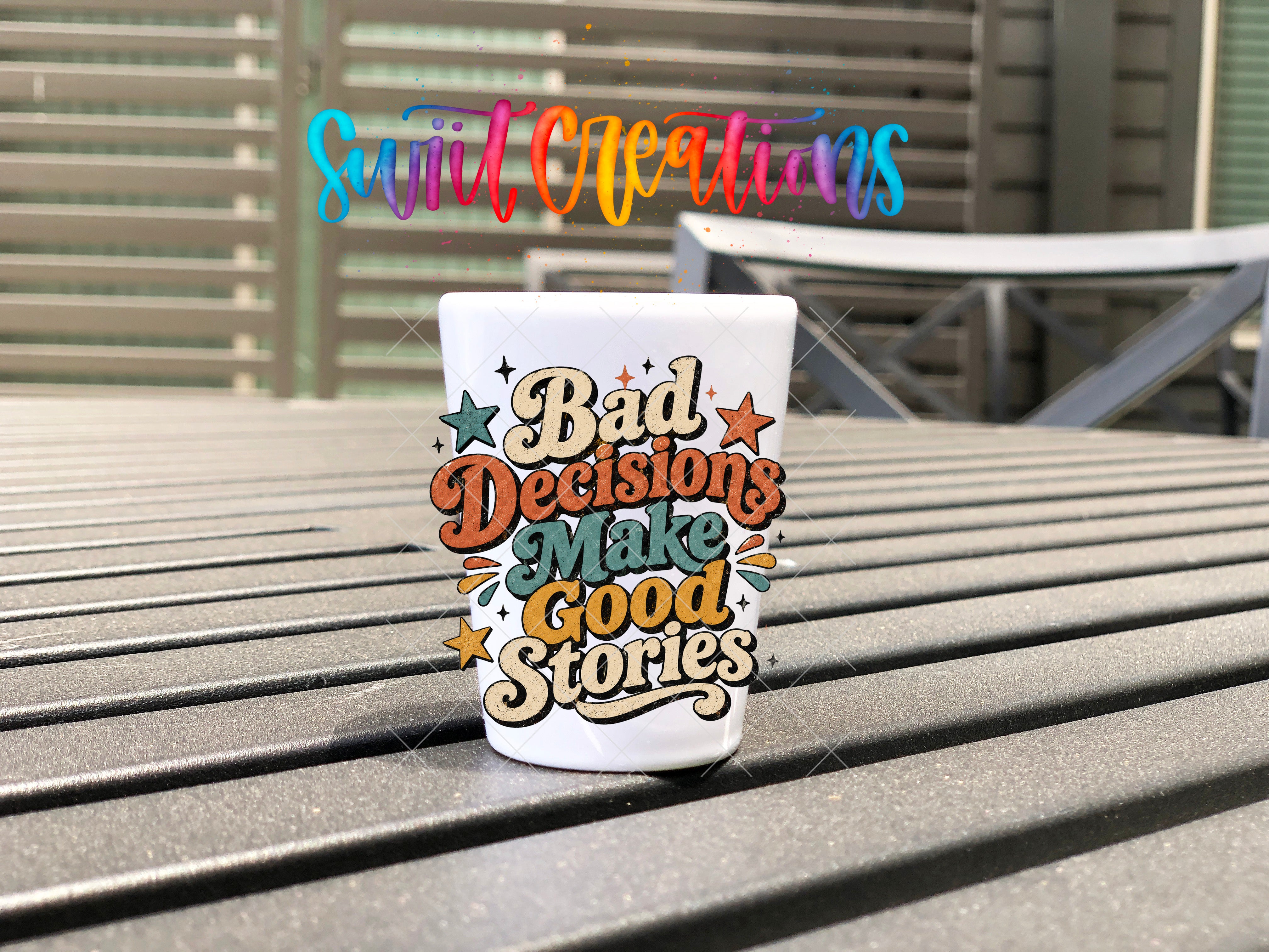 A white mug with colorful text that says "Bad Decisions Make Good Stories" is placed on a wooden surface.