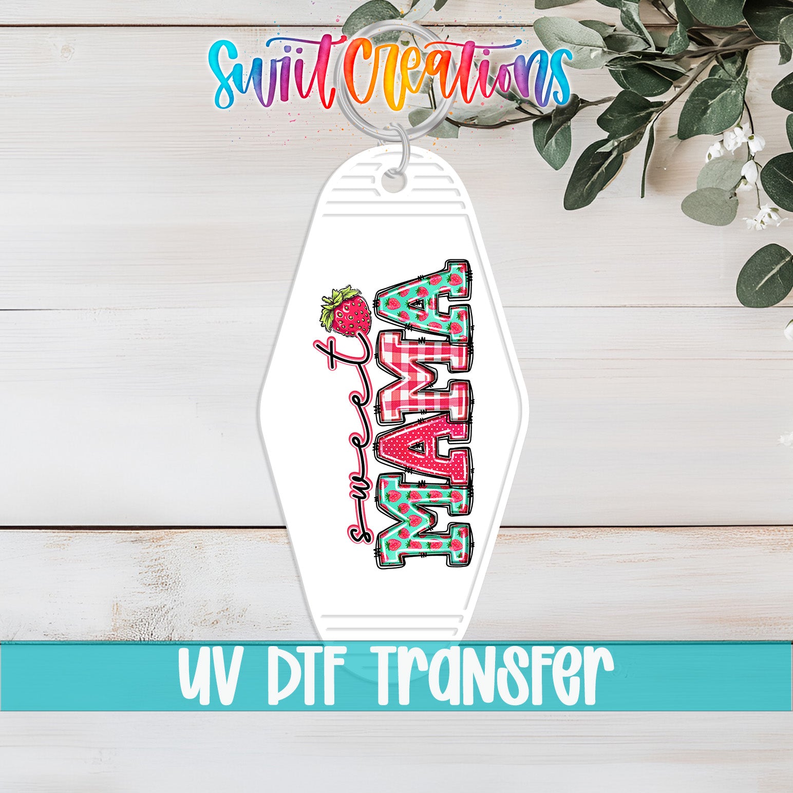 A keychain with the word "MAMA" printed on it, along with a strawberry graphic. The keychain is placed on a wooden surface, and there is a plant in the background.