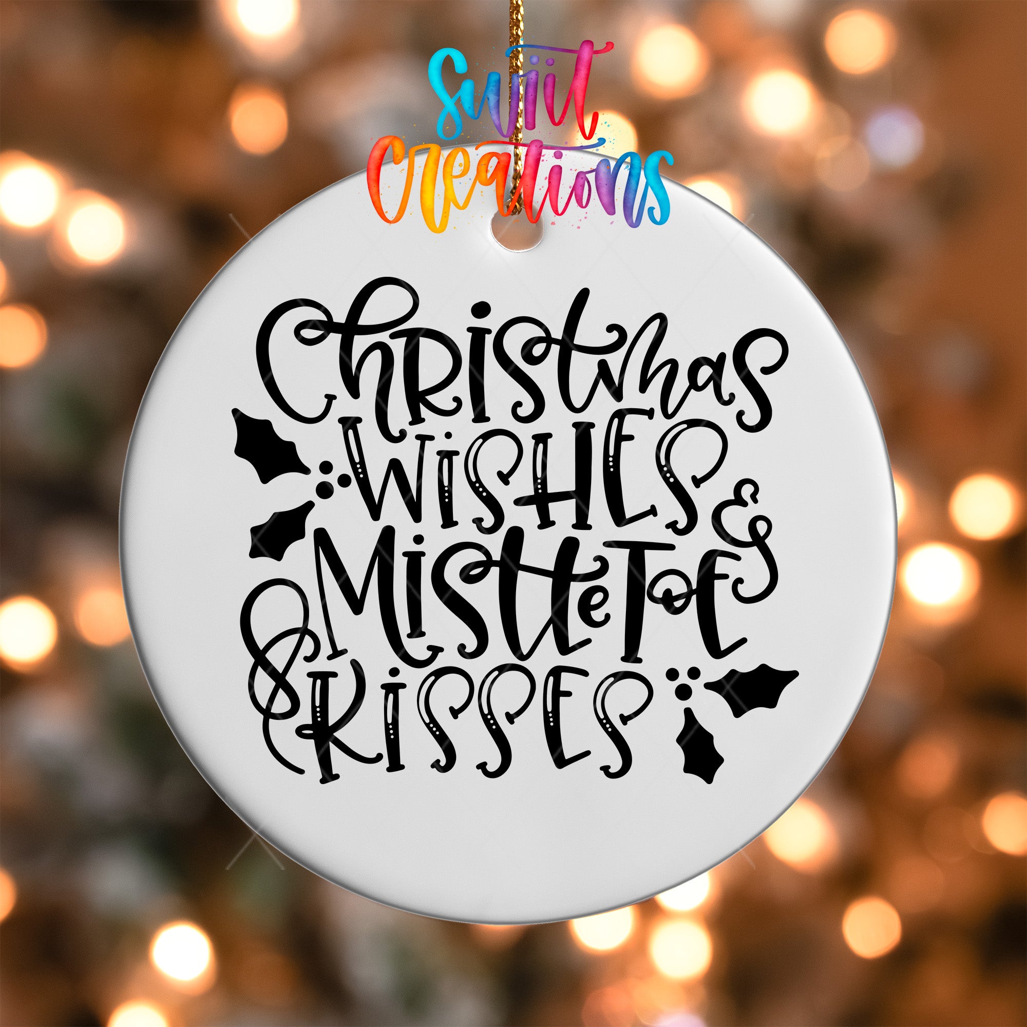 A white ornament with black text that says "Christmas Wishes & Mistle Toes Kisses" hanging on a string.