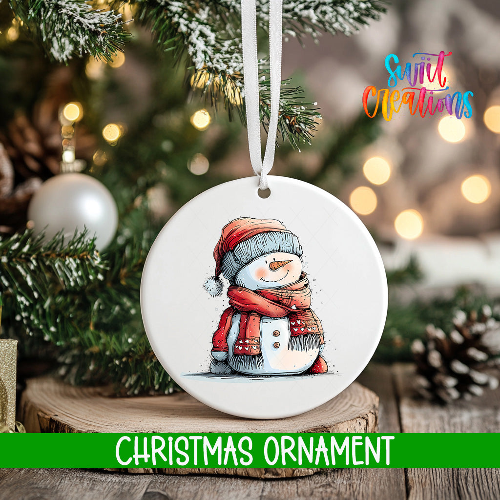 A white Christmas ornament featuring a snowman is hanging from a tree branch, with a blurred background of pine branches and twinkling lights.
