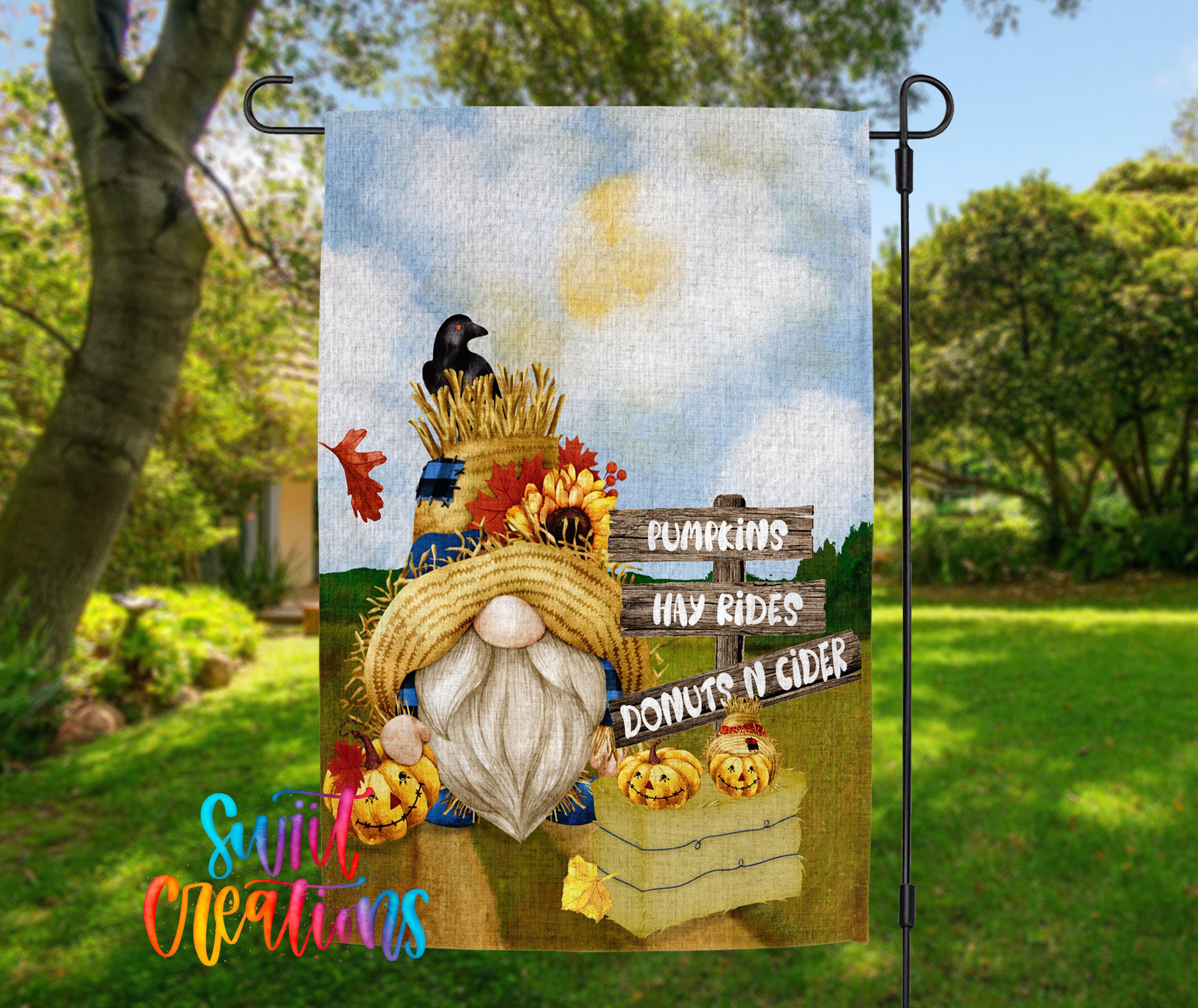 A colorful garden gnome sign with a pumpkin patch and a sign that says "Pumpkins hay rides donuts n cider" is displayed in a garden setting.