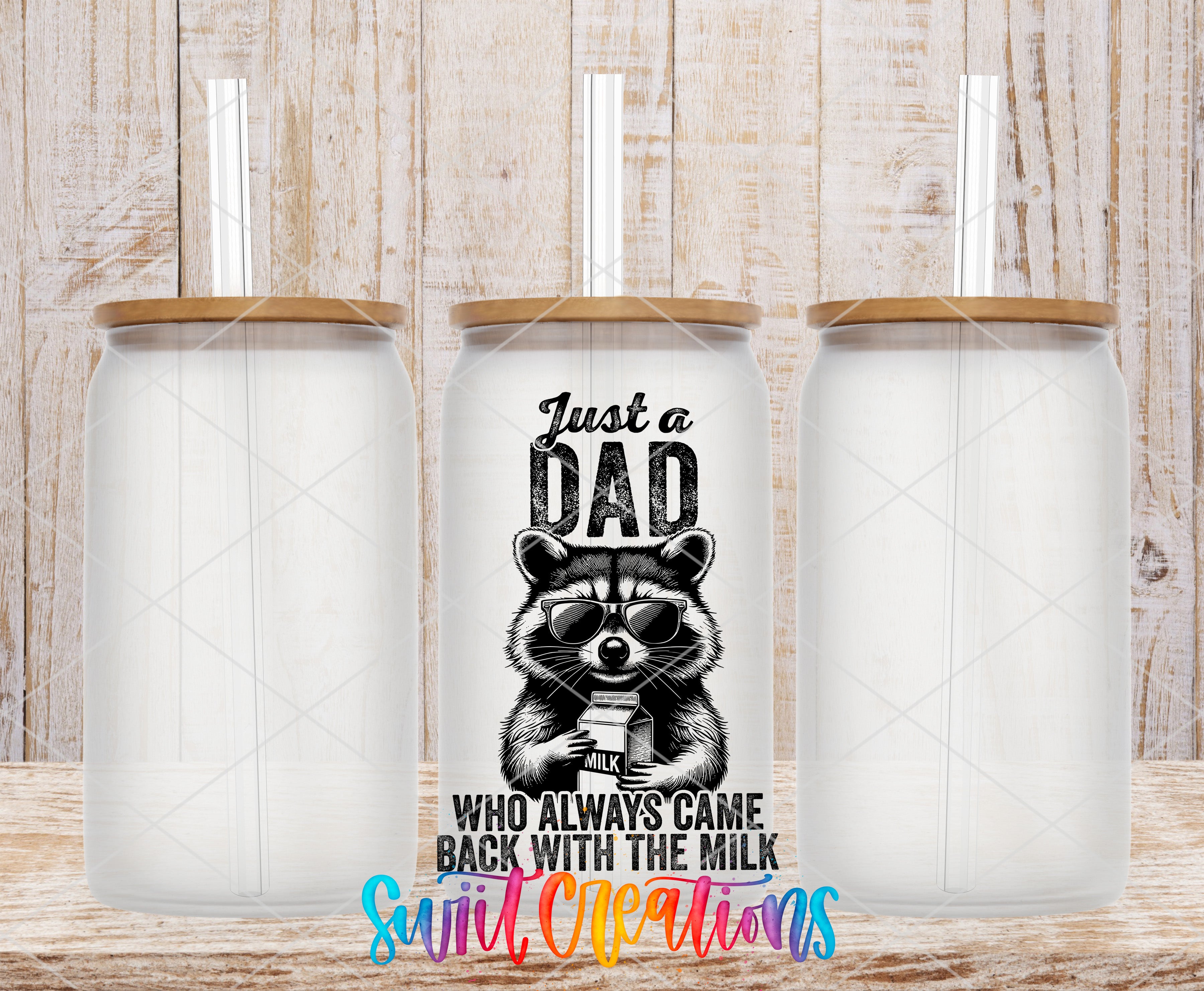 three clear glass tumblers with straws, each with a lid and a printed design on the front. The design includes a raccoon wearing sunglasses and the text "Just a Dad who always came back with the milk" along with the phrase "Who always came back with the milk" written below the raccoon.