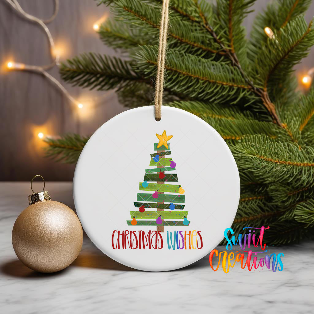A white Christmas tree ornament with a star and colorful ornaments is displayed on a table, accompanied by a gold ornament and a Christmas tree in the background.