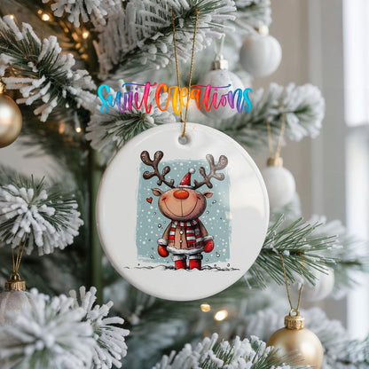 A white Christmas tree decorated with ornaments, including a round ornament featuring a cartoon reindeer wearing a red scarf and hat.