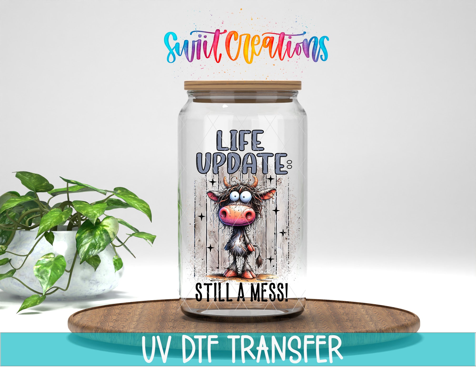 a glass jar with a cartoon cow on it, placed on a wooden surface. The jar has a label that says "LIFE UPDATES STILL A MESS!" and there is a rainbow-colored text above it. The background of the image is white, and there is a potted plant to the left of the jar.