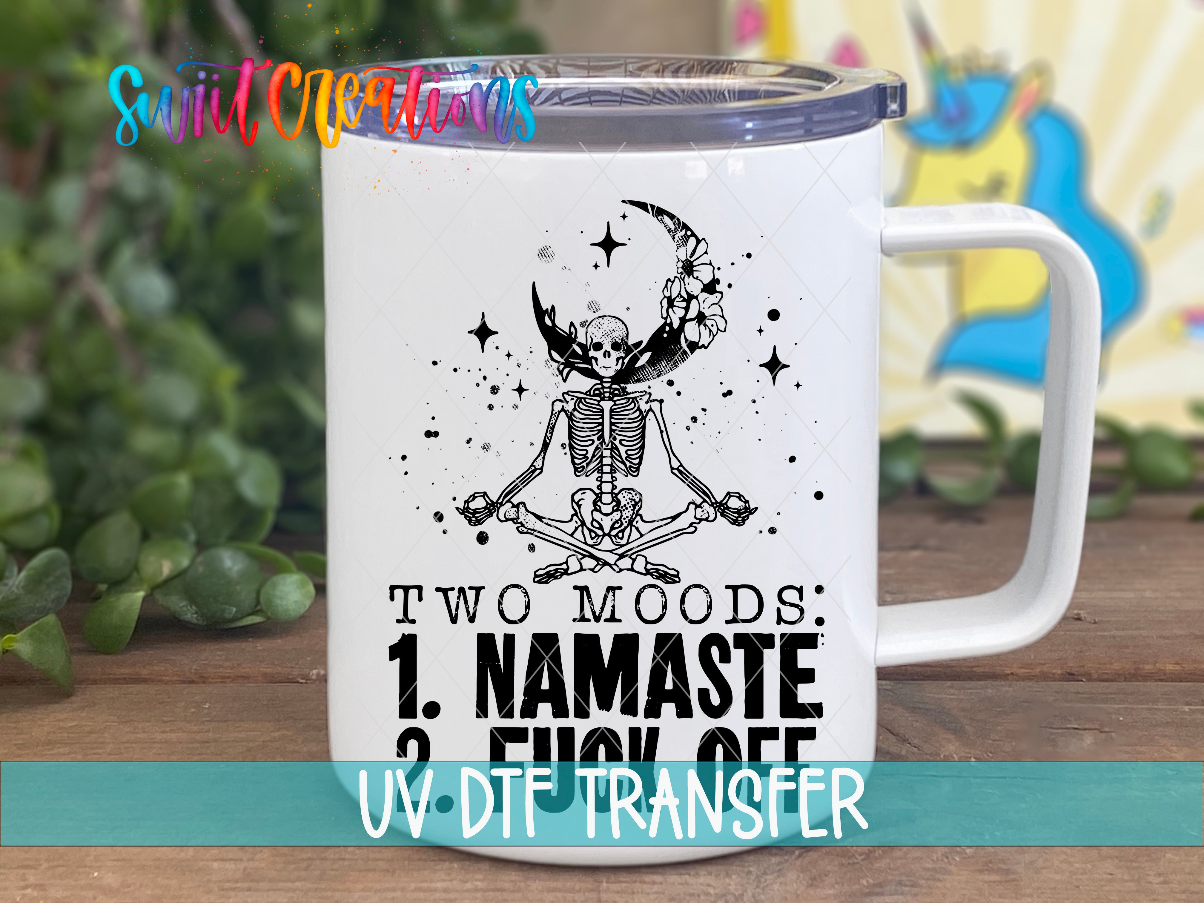 A white mug with a black and white illustration of a skeleton in a meditative pose, along with the text "Two moods: 1. NAMASTE 2. FUCK OFF" printed on it.