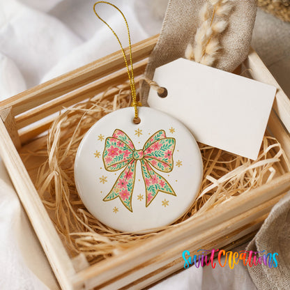 A white ceramic ornament with a floral design and a gold bow is displayed in a wooden crate, accompanied by a white tag.