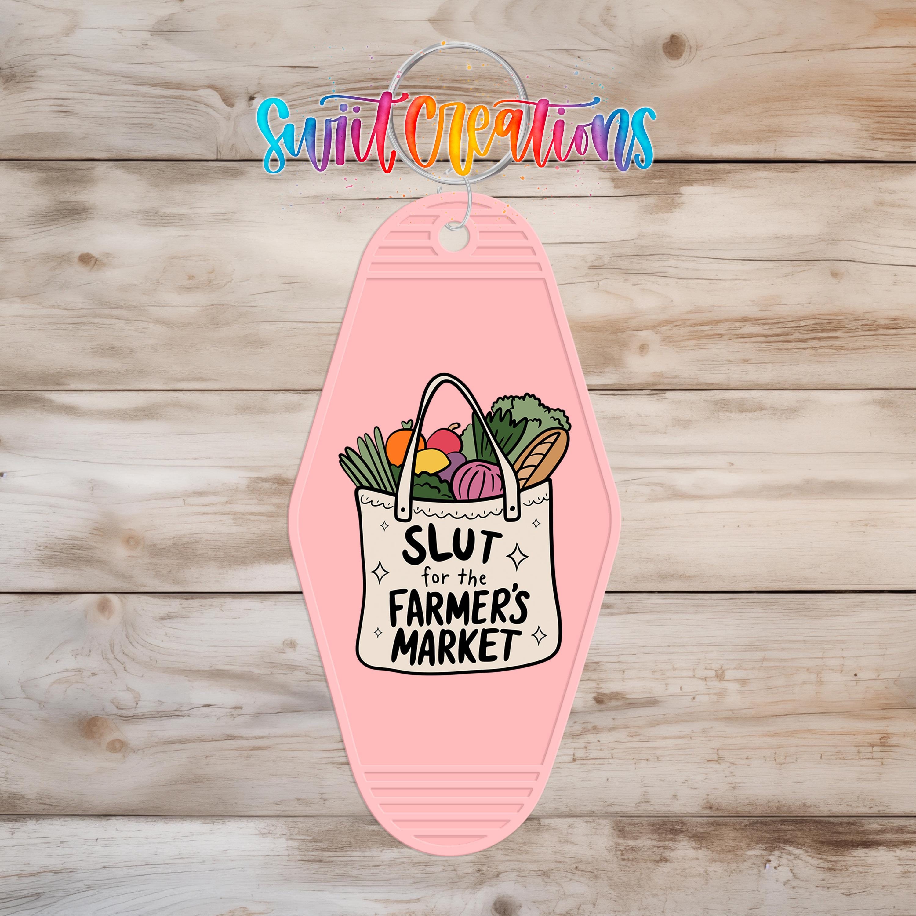 A pink keychain with a bag of vegetables and the text "SLUT for the FARMERS MARKET" printed on it.