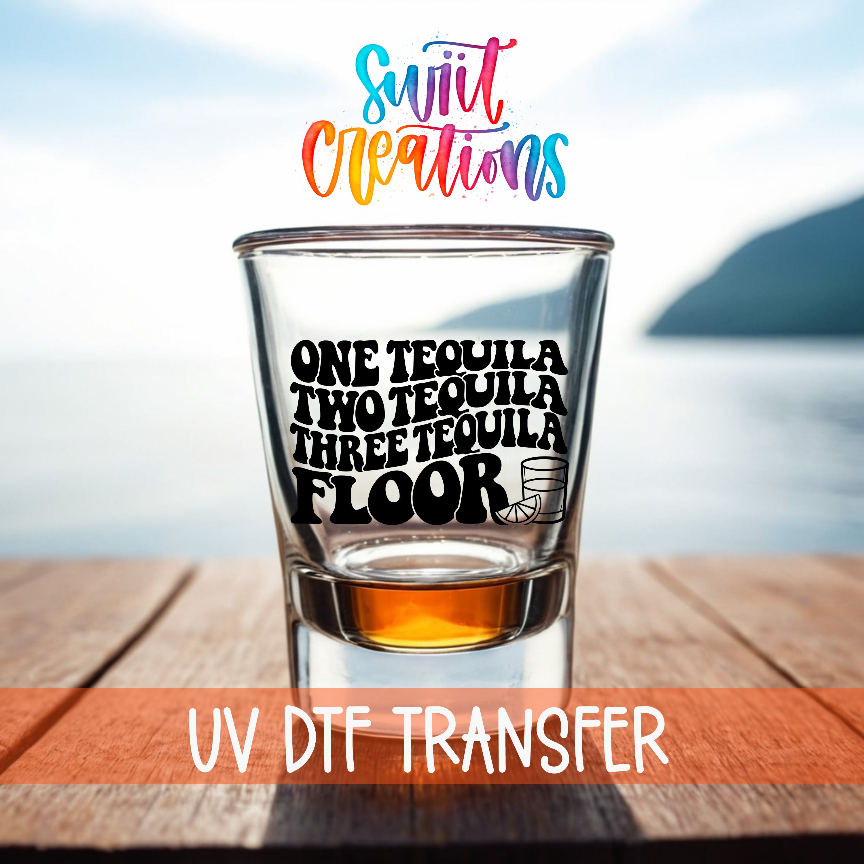 A shot glass with text on it, placed on a wooden surface with a body of water in the background.