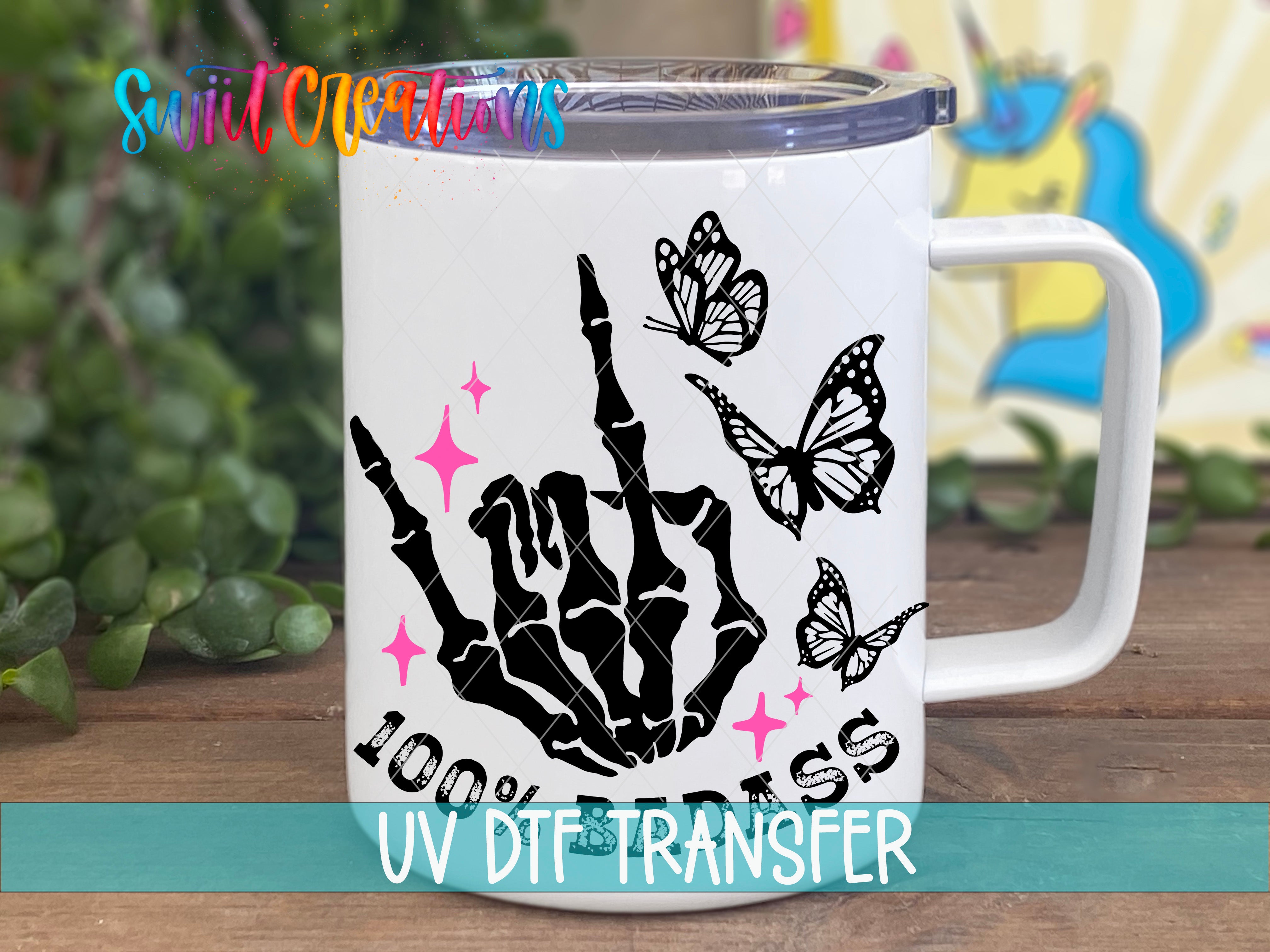 A white mug with a black skeleton hand and butterflies printed on it, along with the text "100% DTS" and "UV DTSTRANSFER".