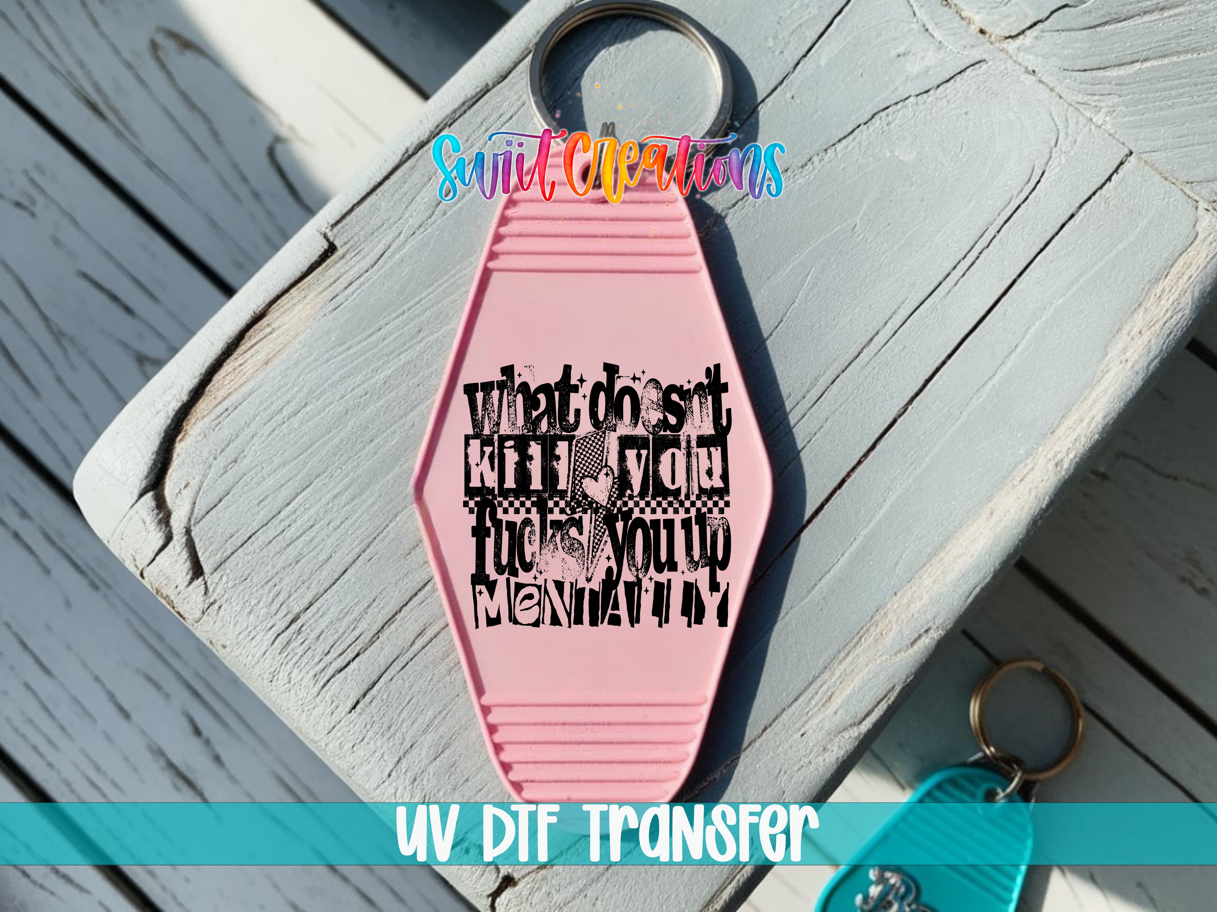 A pink keychain with a black text design on it, placed on a wooden surface.