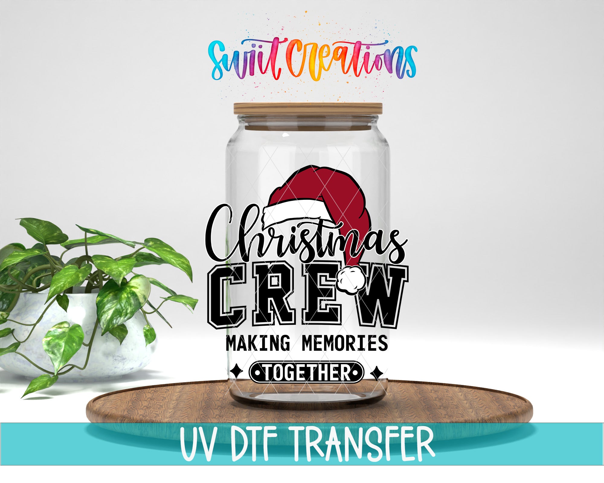 A glass jar with a Christmas-themed design, including a Santa hat, and the text "Christmas CREW Making memories together" printed on it. The jar is placed on a wooden tray, and there is a potted plant in the background.