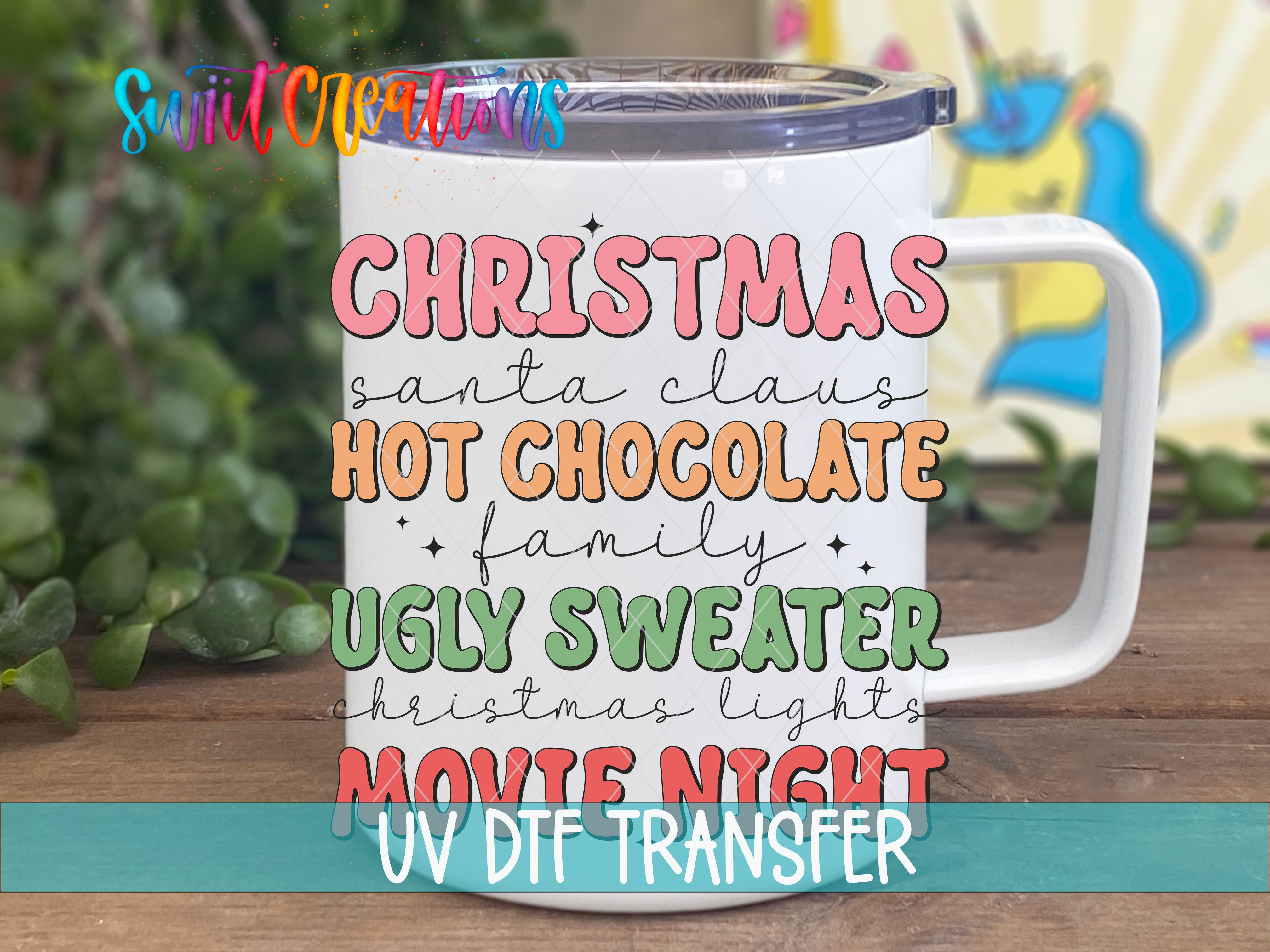 A white mug with colorful text that says "CHRISTMAS santa claus HOT CHOCOLATE family UGLY SWETTER christmas lights MOVIE NIGHT UV DFT TRANSFER"