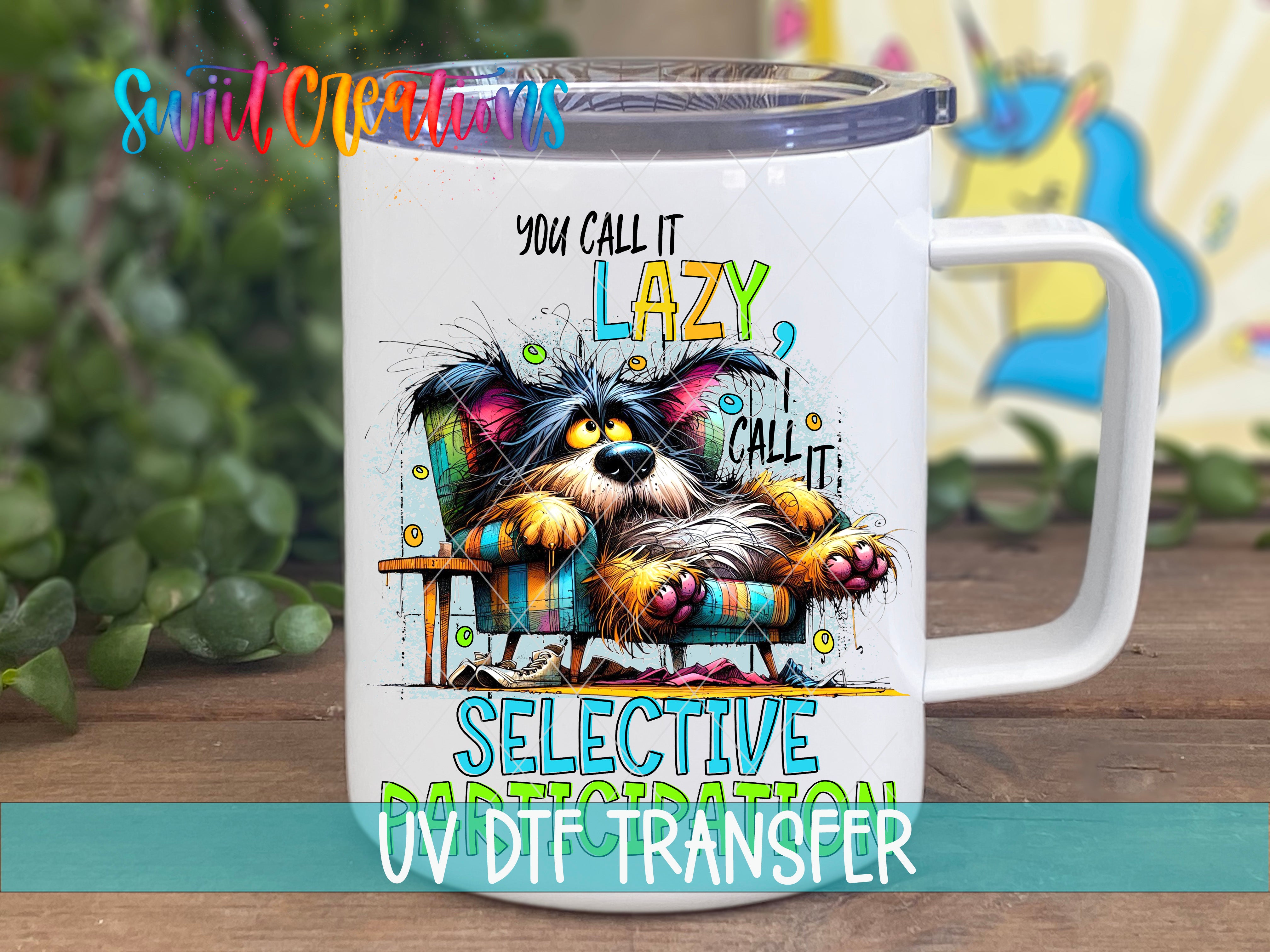 A white mug with a colorful illustration of a dog sitting in a chair and making a funny face. The mug has a lid and a handle, and there is text on it that says "You call it lazy, I call it selective UV transfer".