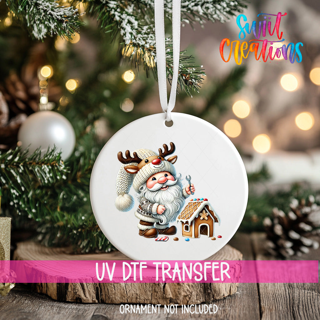 A white ornament with a Santa Claus and reindeer design hangs on a Christmas tree, surrounded by pine branches and twinkling lights.