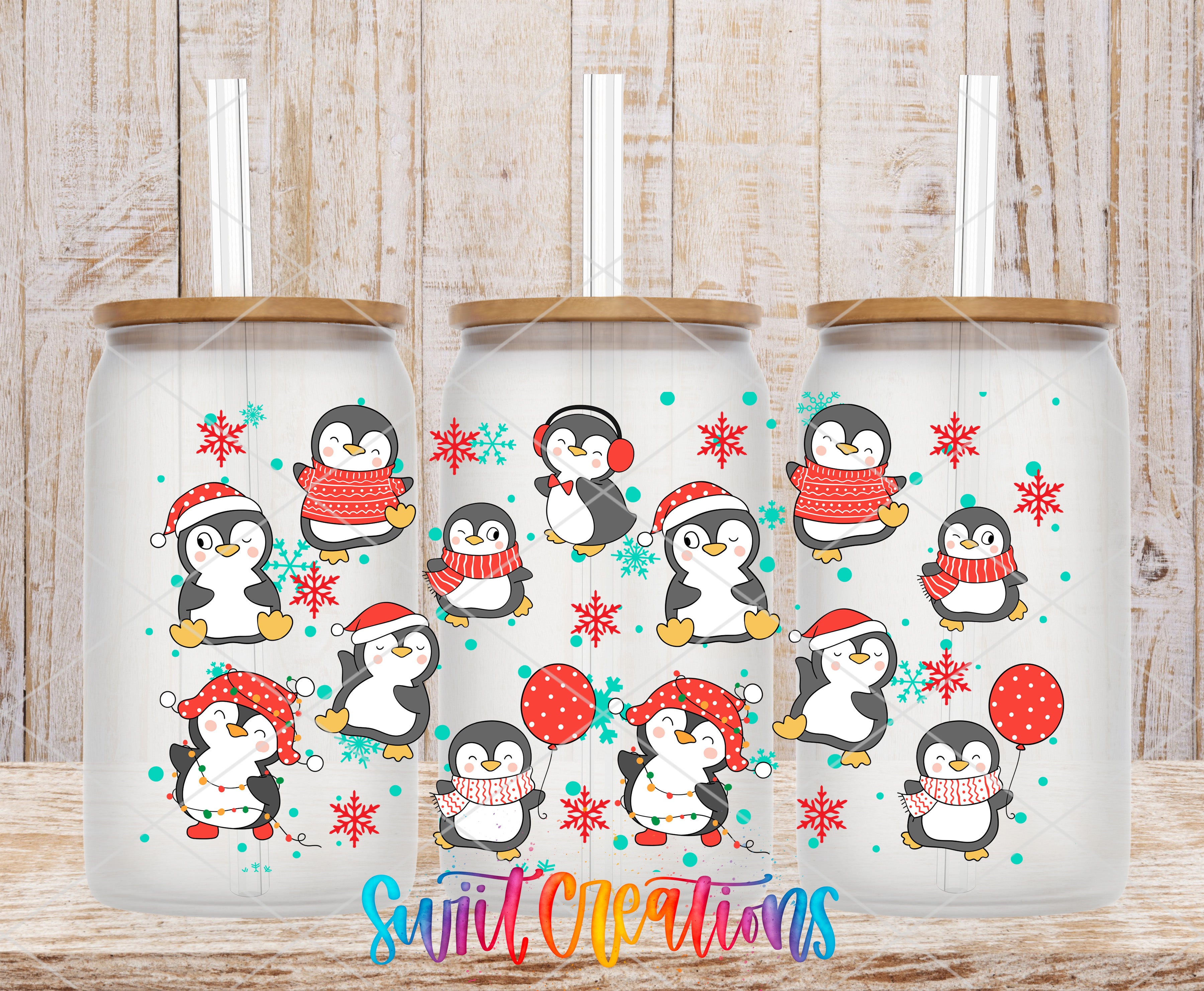 A collection of three glass tumblers with a festive design featuring cartoon penguins and snowflakes.