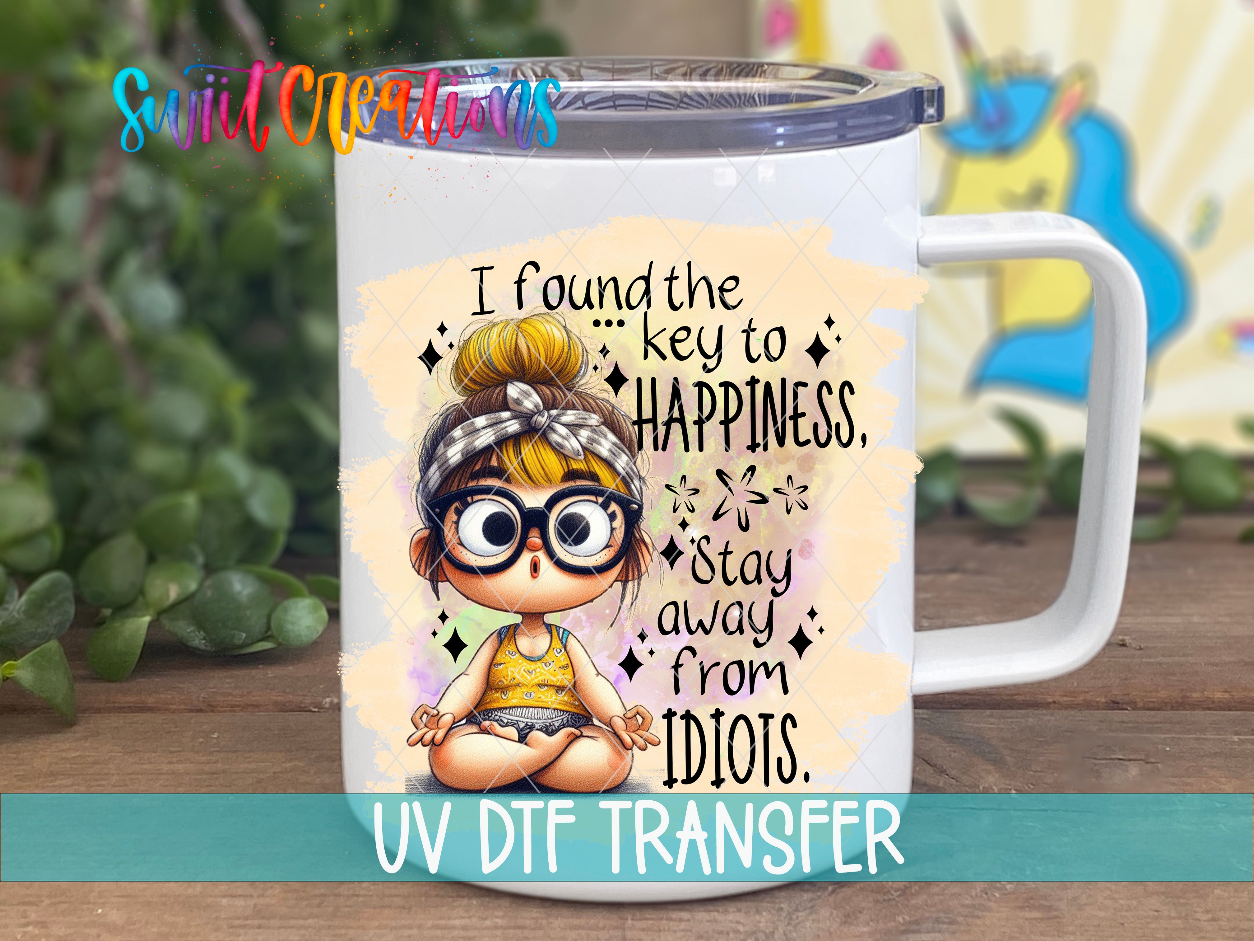 A white mug with a printed design featuring a cartoon girl with glasses and a bow in her hair, along with text that says "I found the key to happiness. Stay away from Idiots."