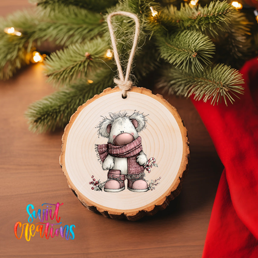A wooden ornament featuring a cartoon image of a white dog wearing a pink scarf and boots, hanging on a Christmas tree.