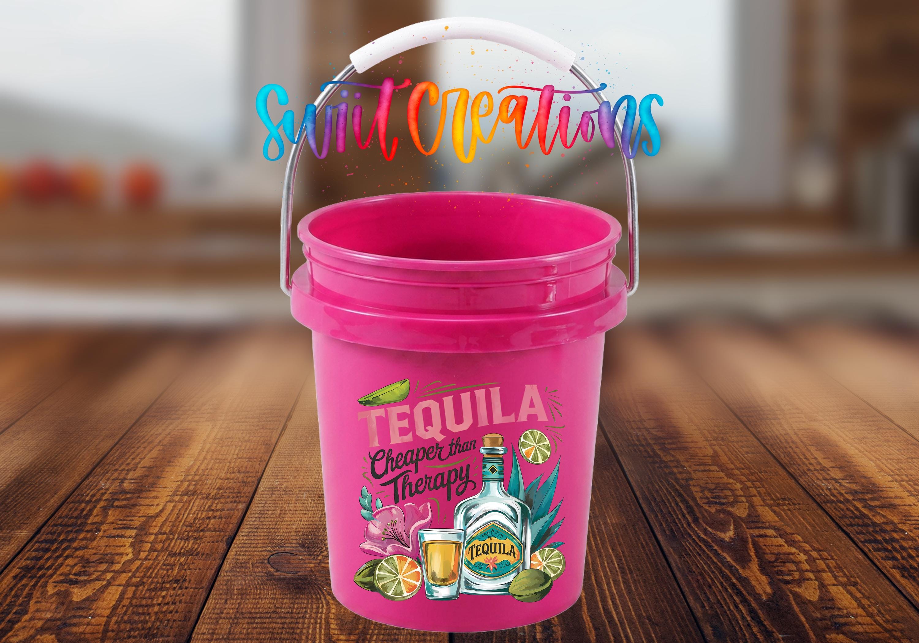 A pink bucket with a tequila-themed design, featuring a bottle of tequila, a lime, and other tequila-related items, along with the text "Tequila Cheaper Therapy".