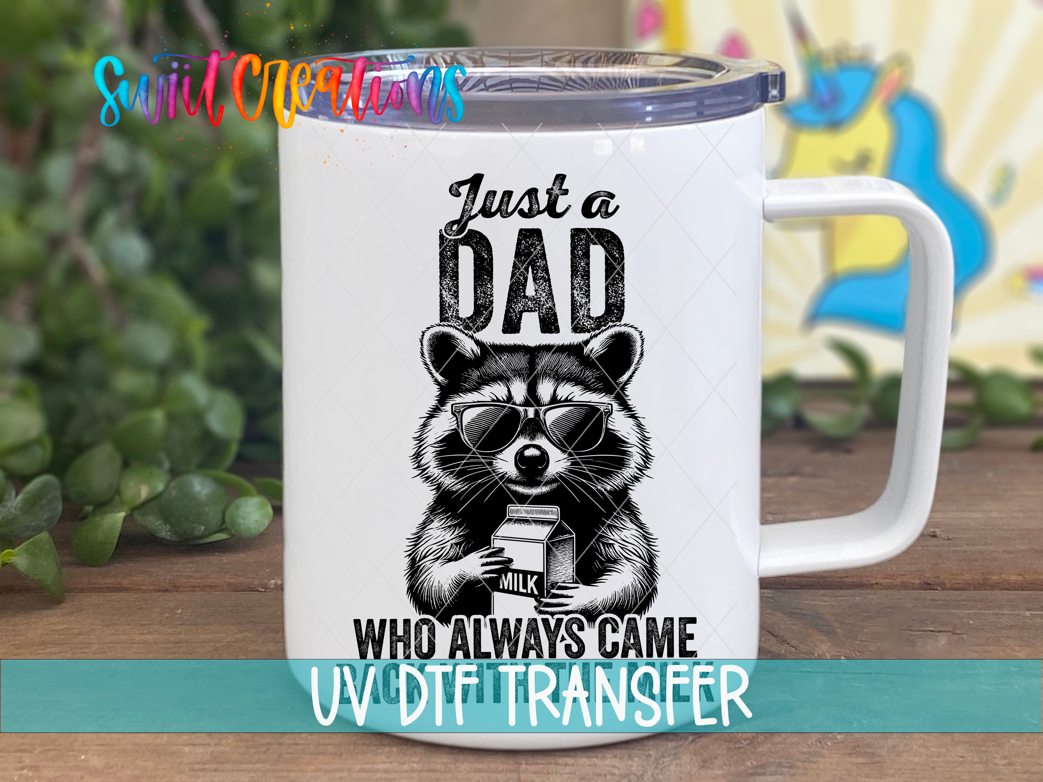 A white mug with a black and white illustration of a raccoon wearing sunglasses and holding a carton of milk, along with the text "Just a Dad WHO ALWAYS COME UV DFT Transfer".